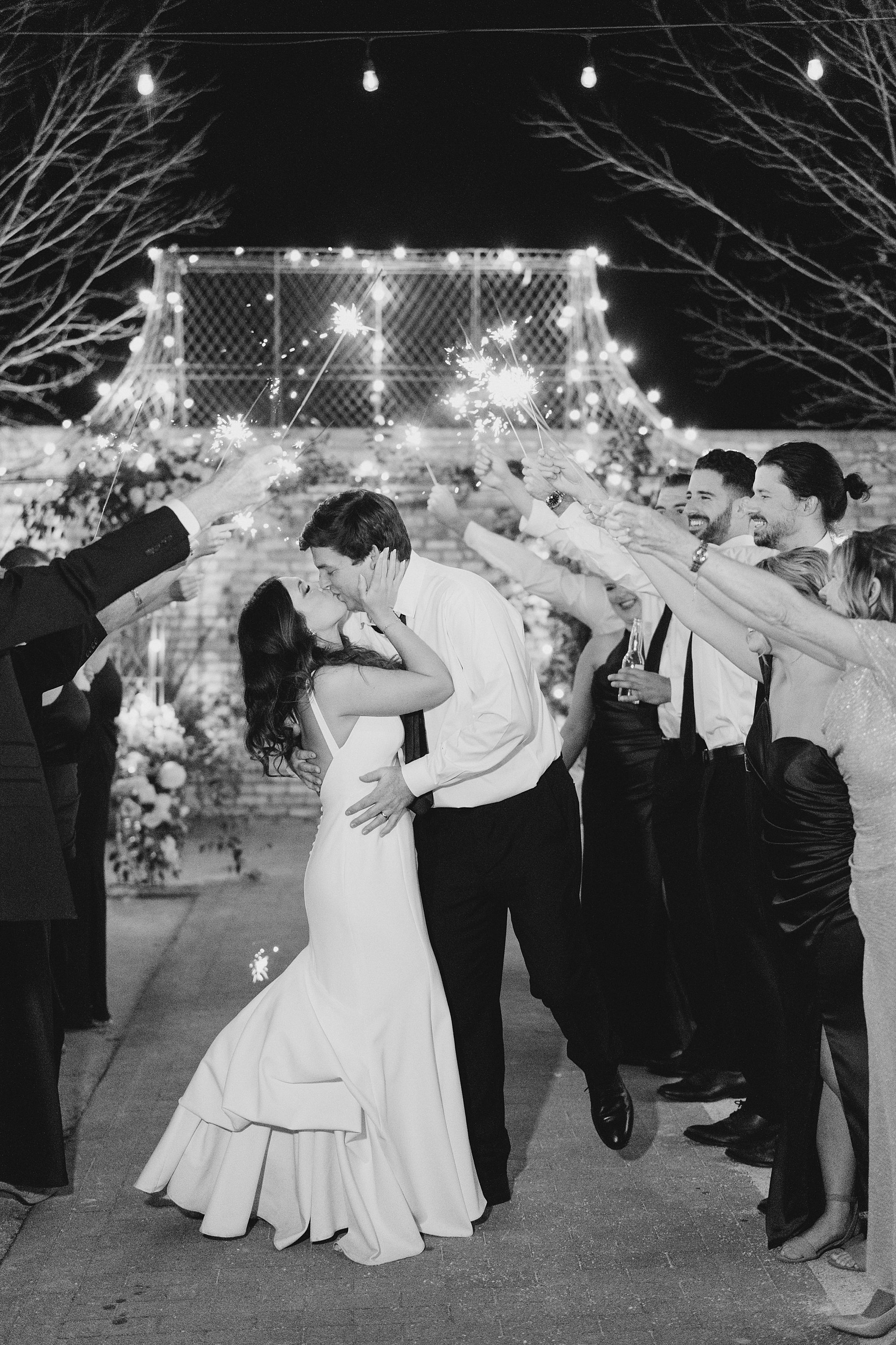 newlyweds kiss as everyone holds up sparklers