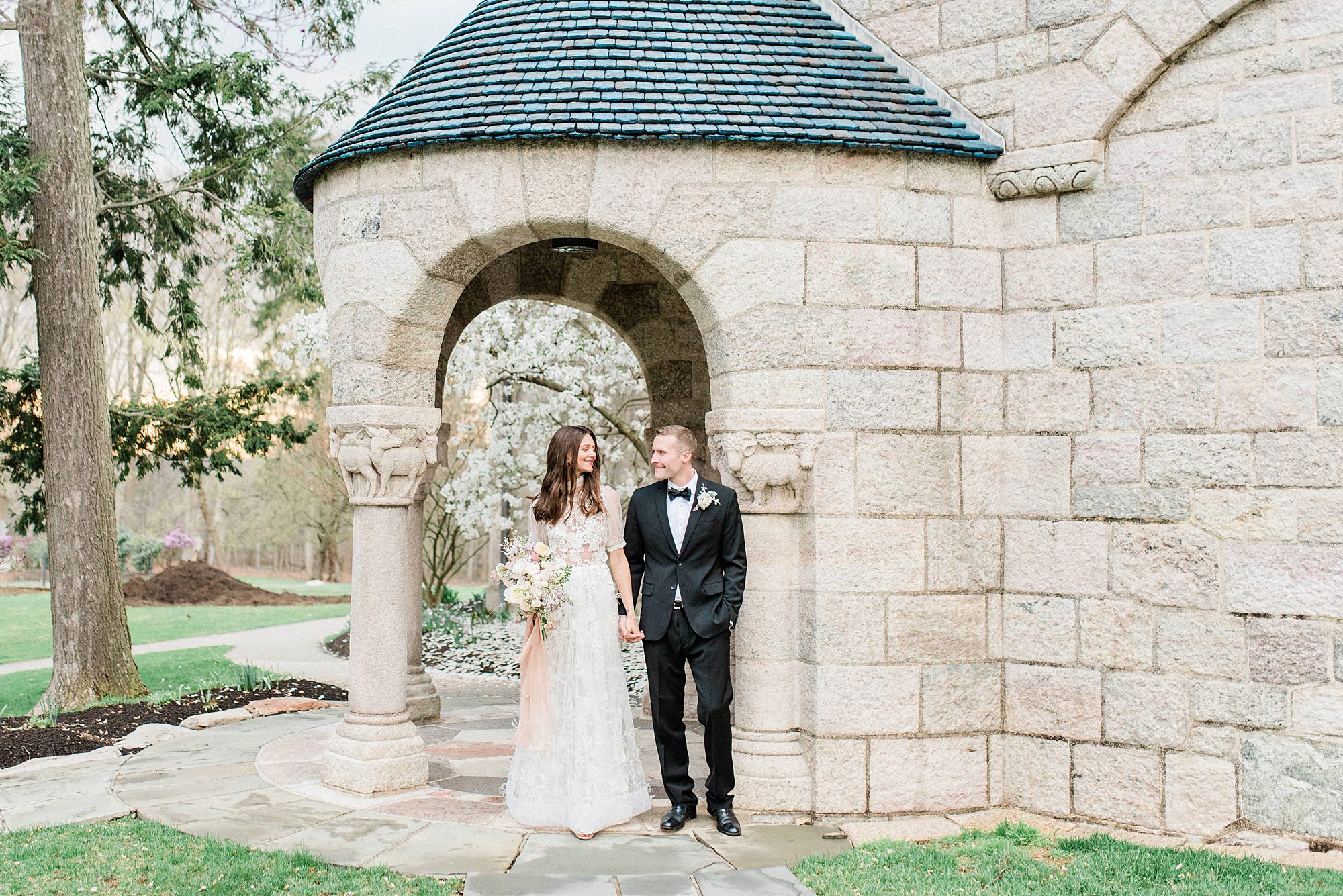 bride and groom under stone archway 