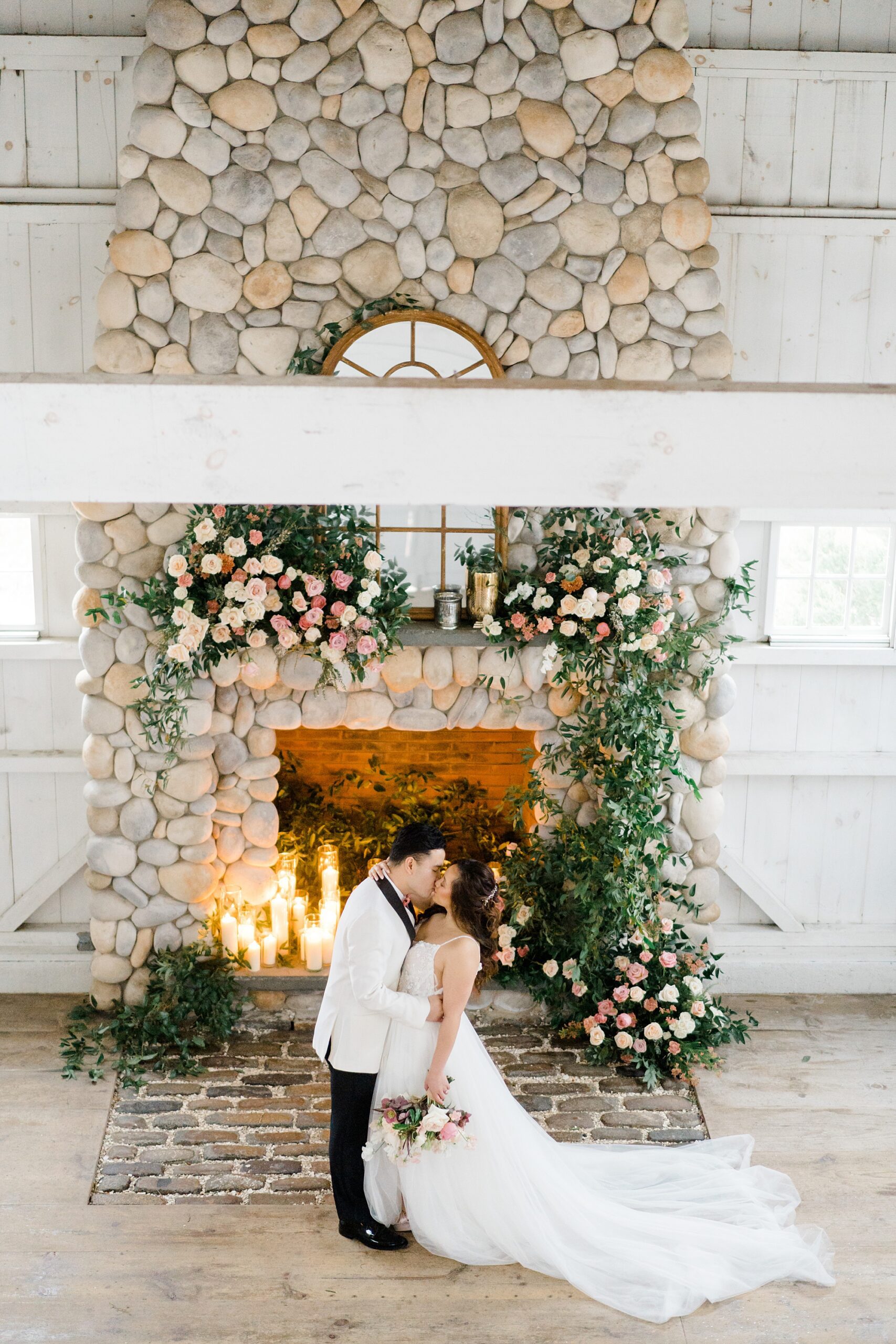bride and groom kiss in front of stone fireplace 