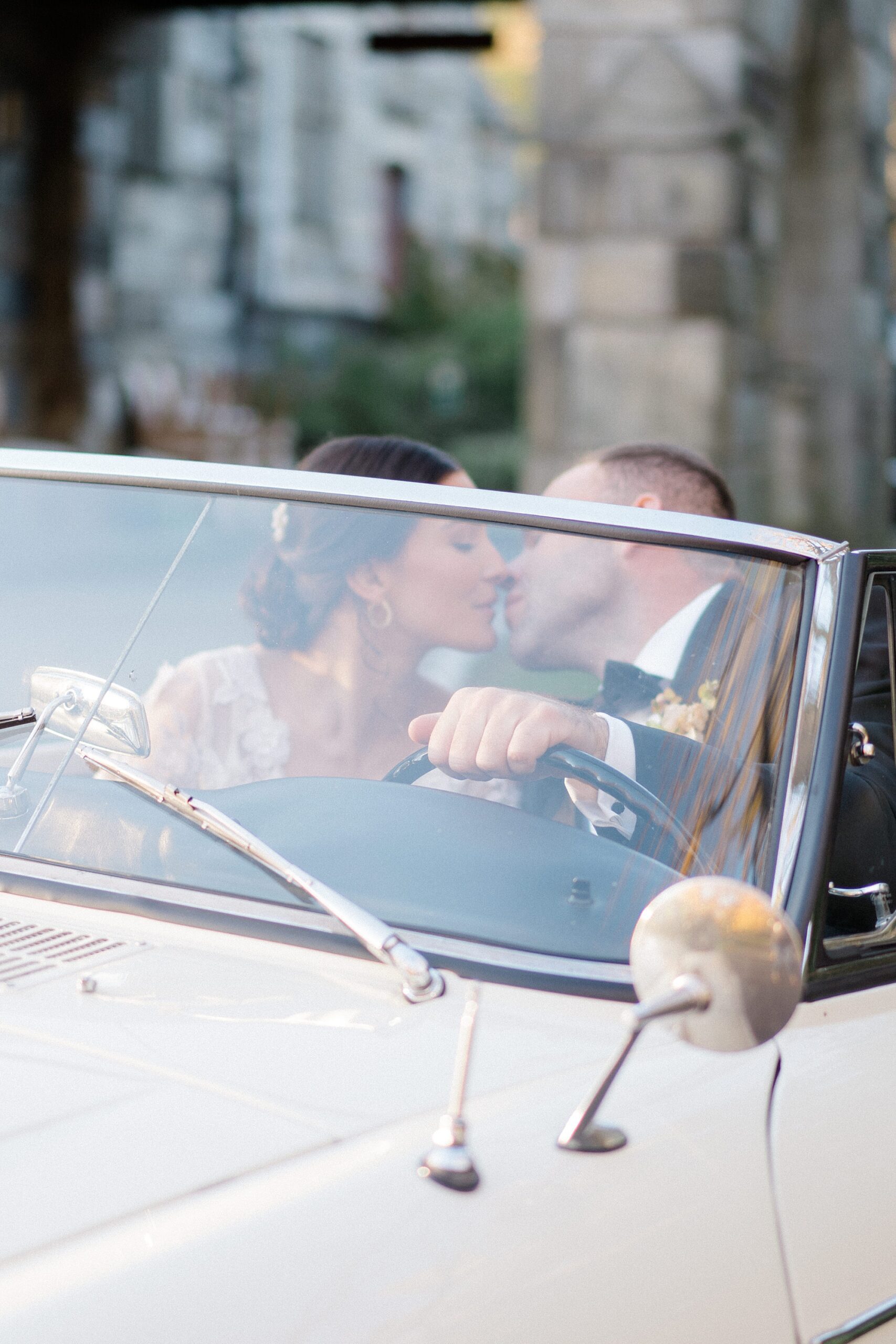 bride and groom kiss in classic car