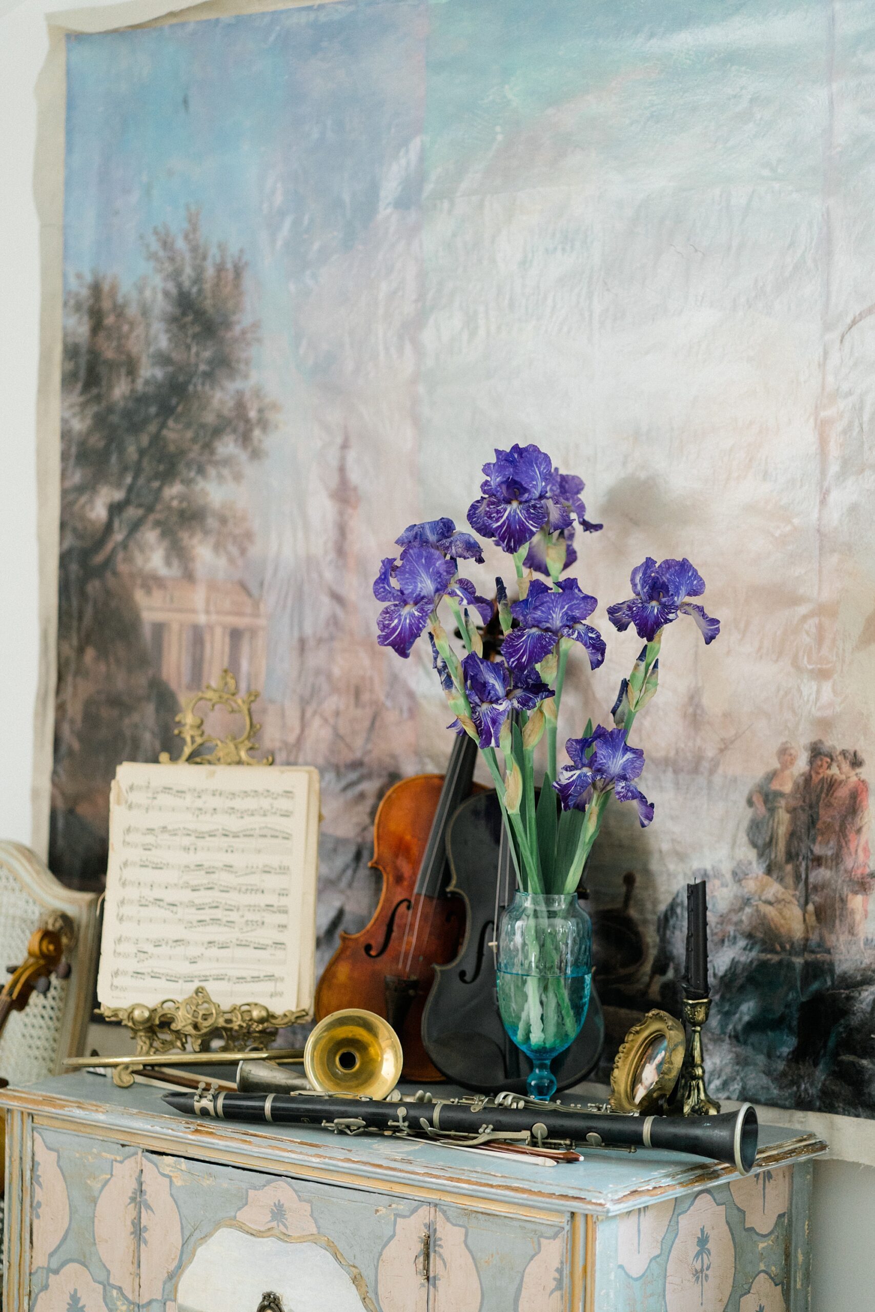 purple flowers in vase by musical instruments