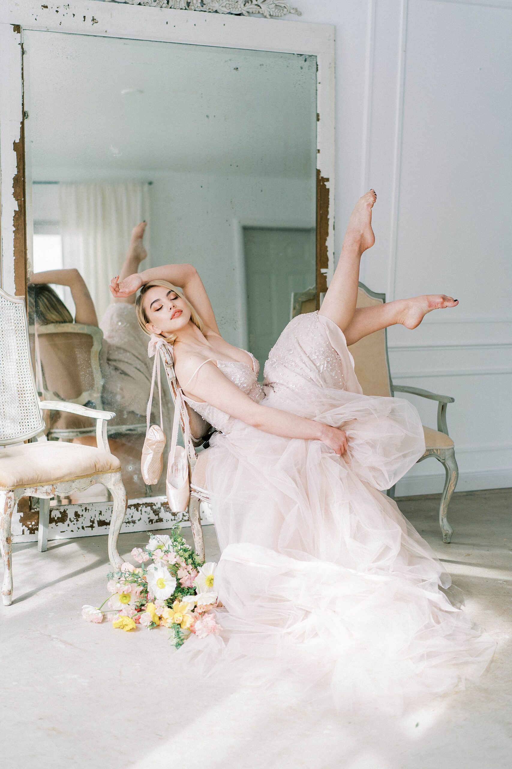 bride lounges in chair with toes pointed in  Ballet-Inspired Bridal Shoot
