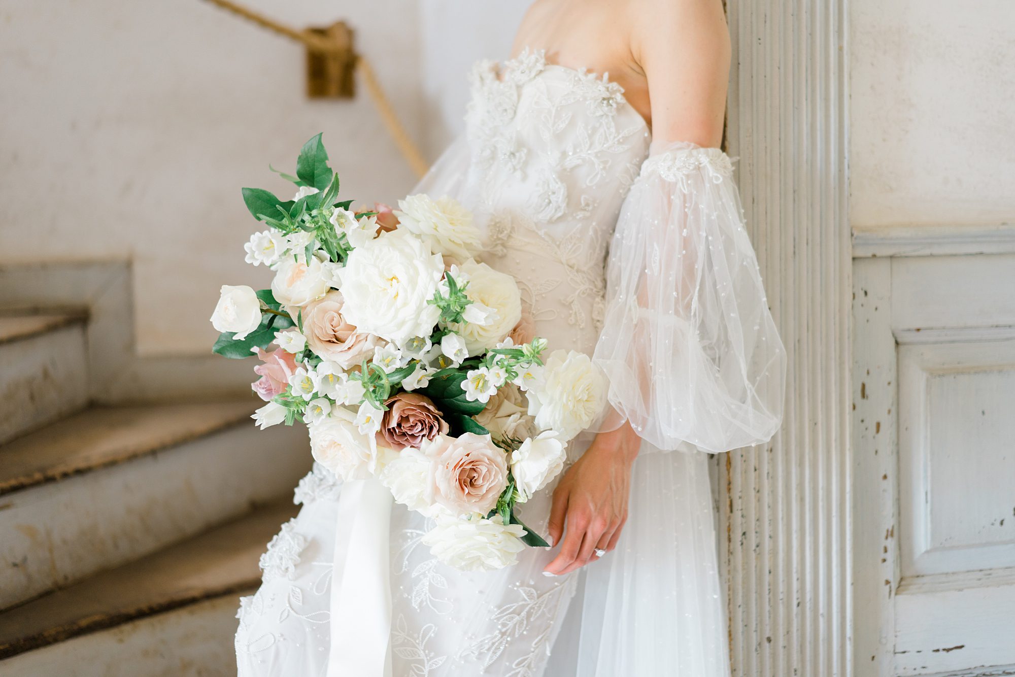 bride leans against wall holding bouquet