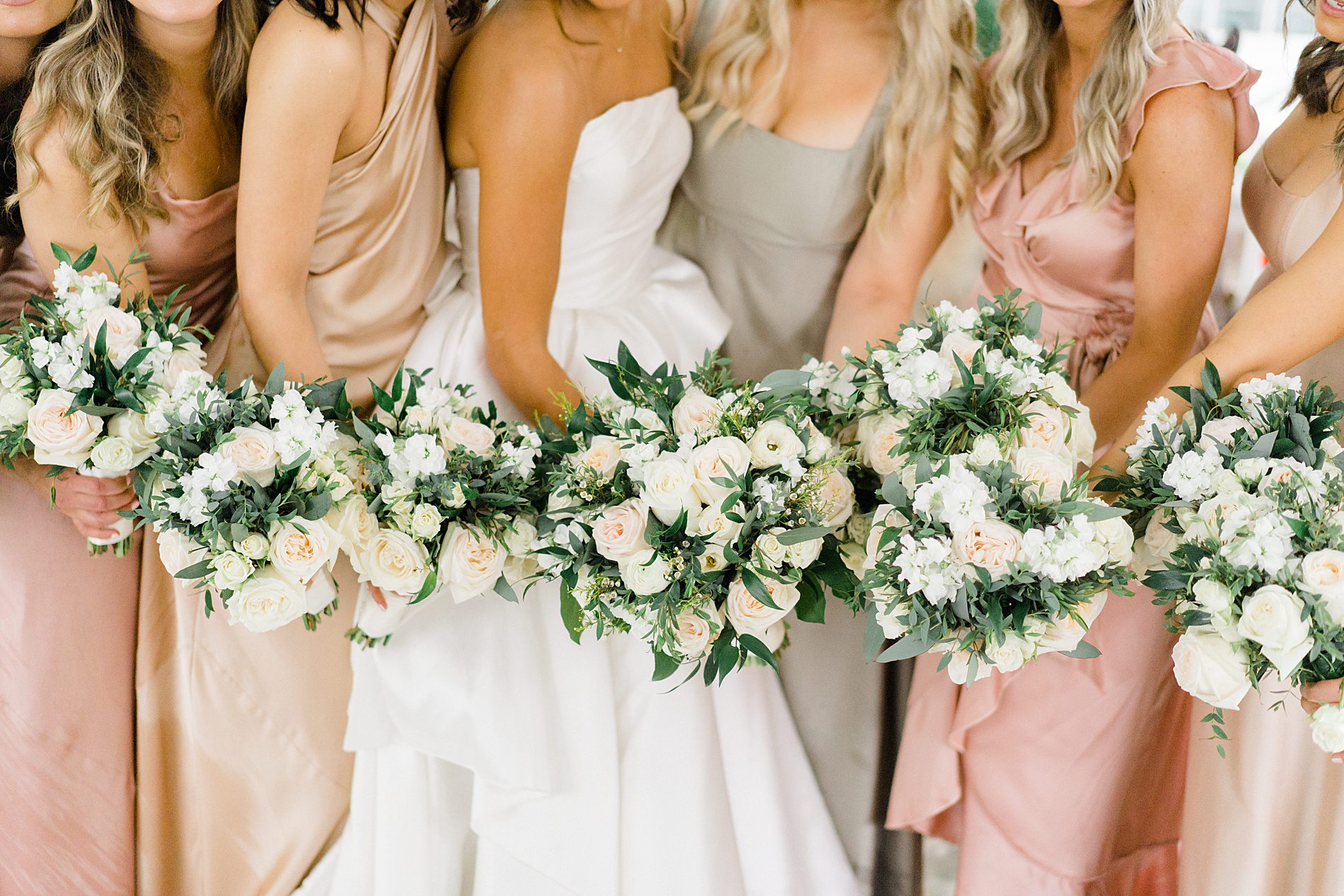 bridesmaids in elegant dresses holding classic wedding bouquets 