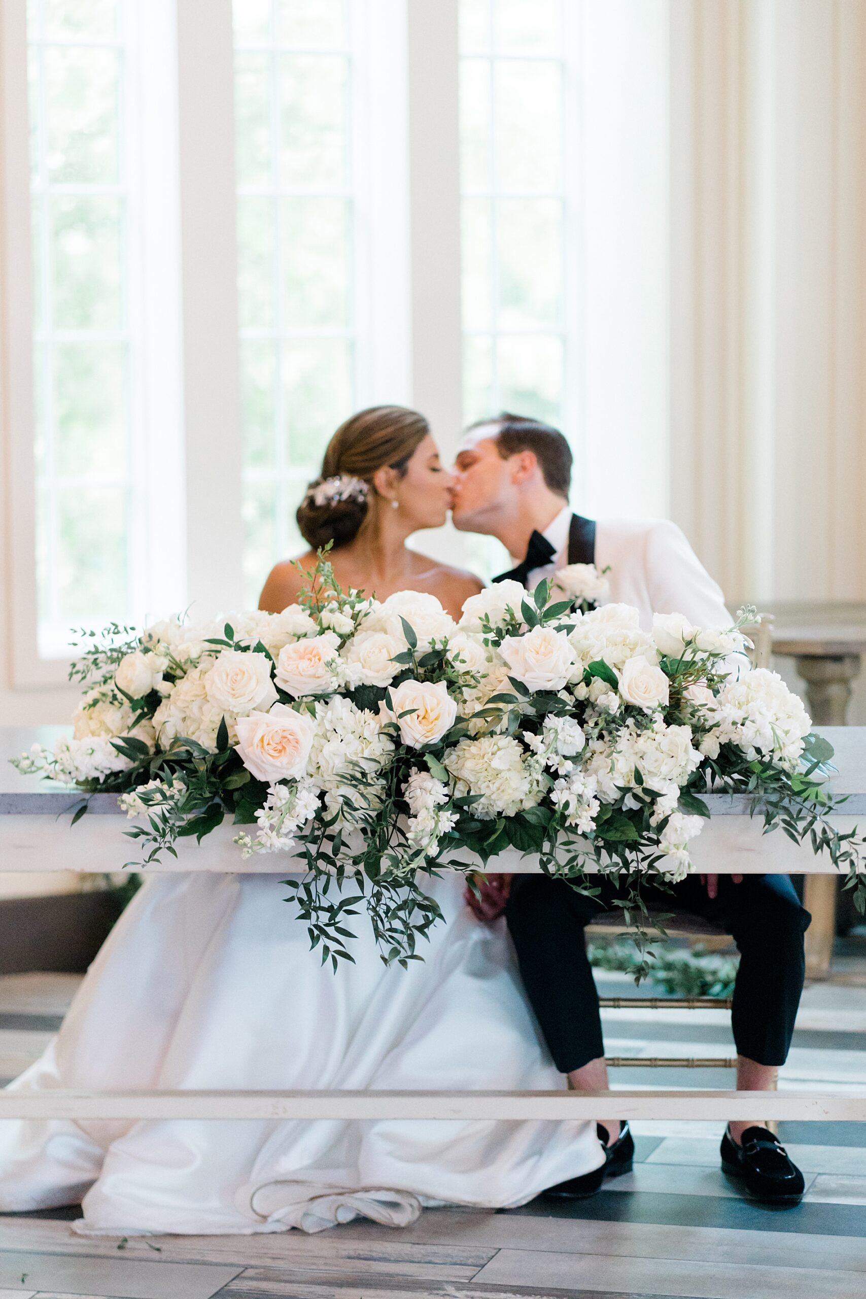 bride and groom kiss at head table from Elegant Coach House Wedding reception