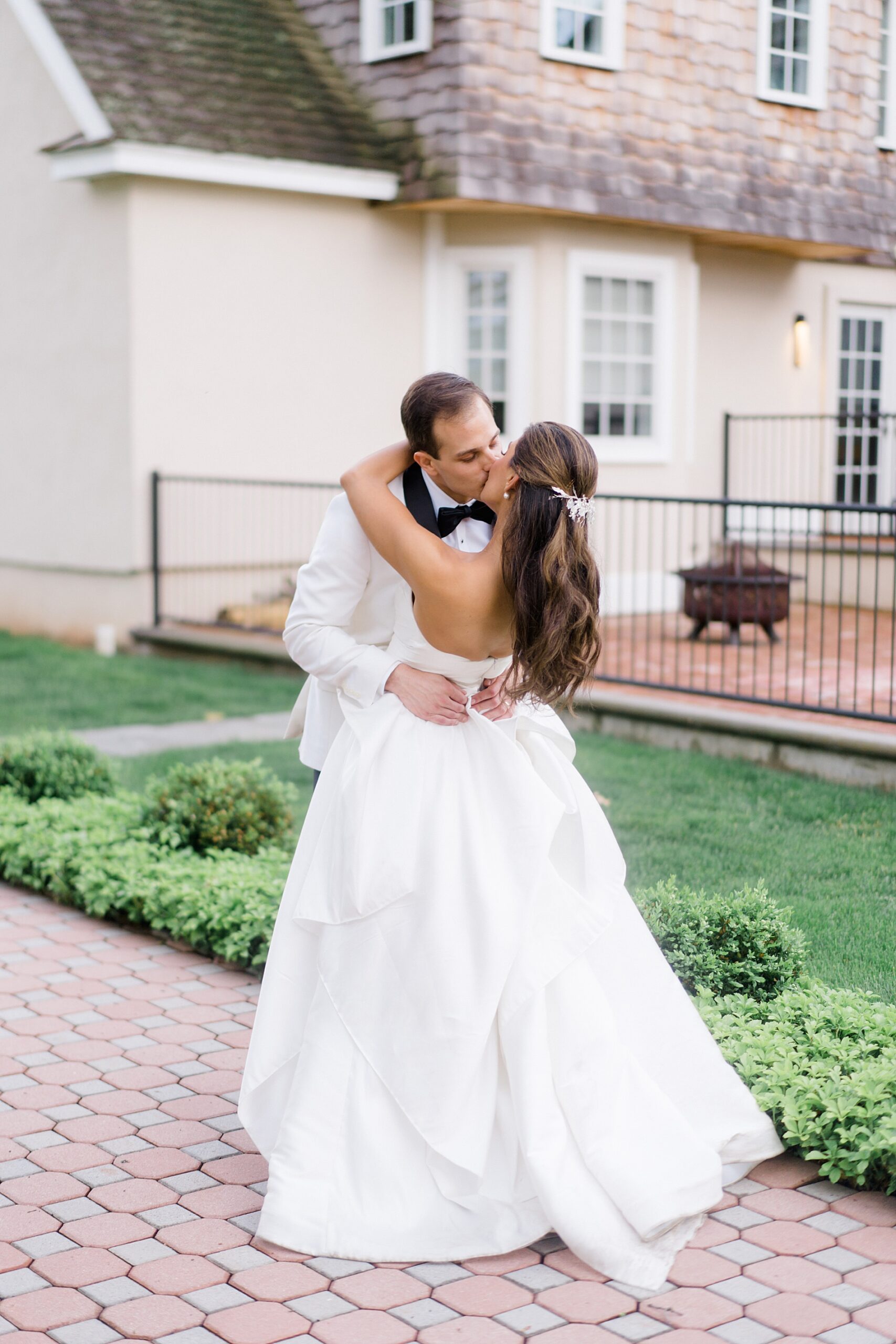 newlyweds kiss outside of the Coach House at the Ryland Inn