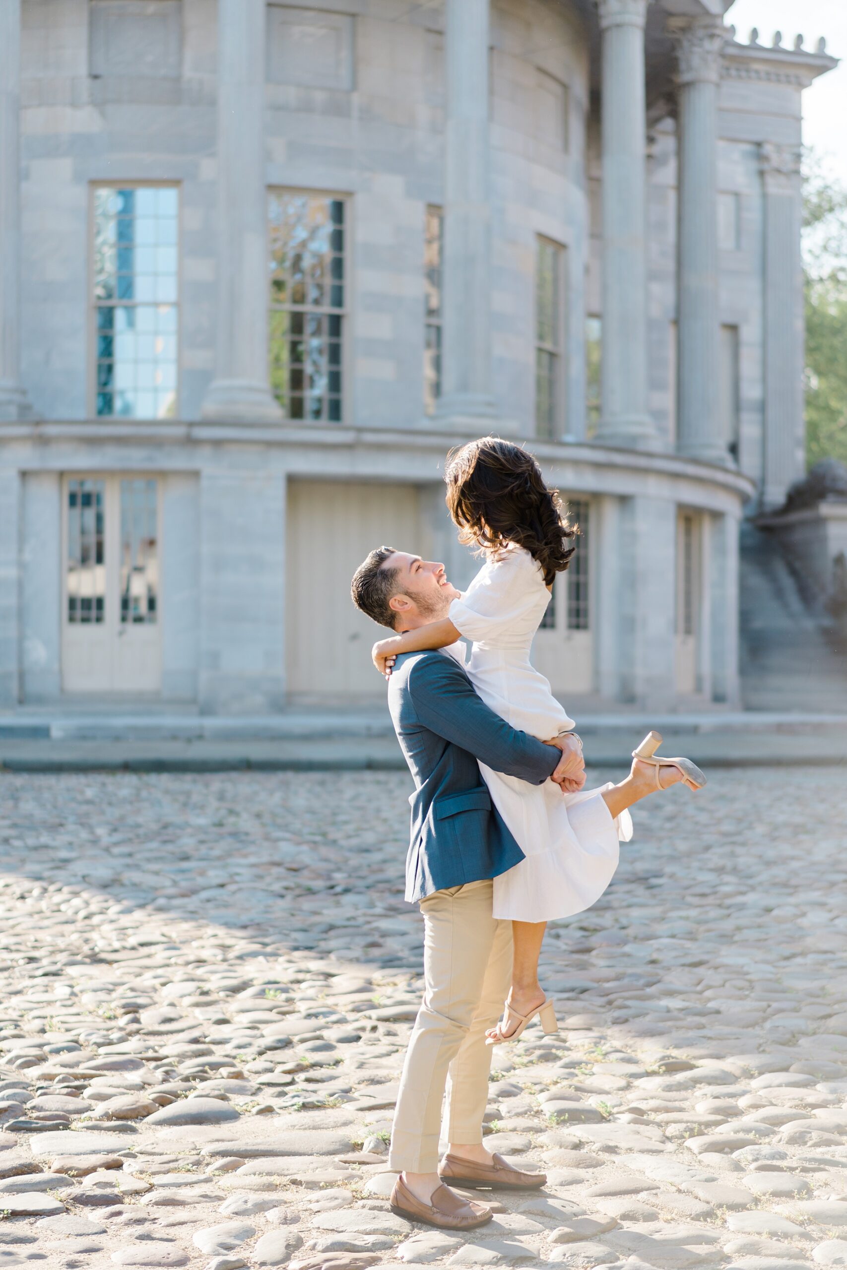 man lifts up his fiance in front of the Merchants Exchange Building