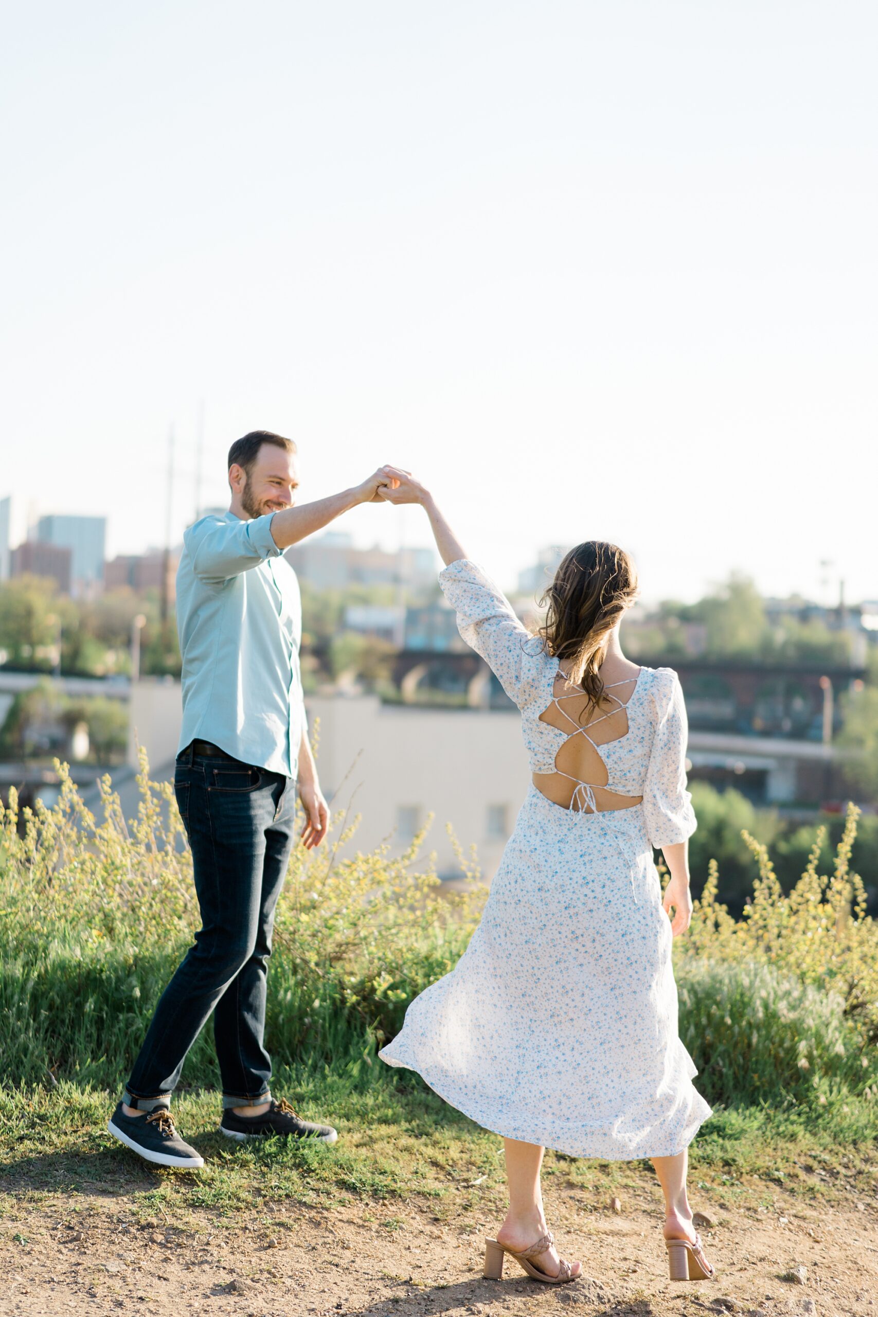 engaged couple dance on top of hill overlooking downtown Philadelphia