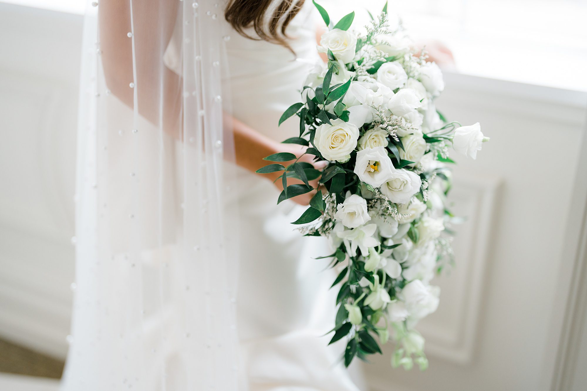 bride holding elegant bridal bouquet of cascading white flowers 
