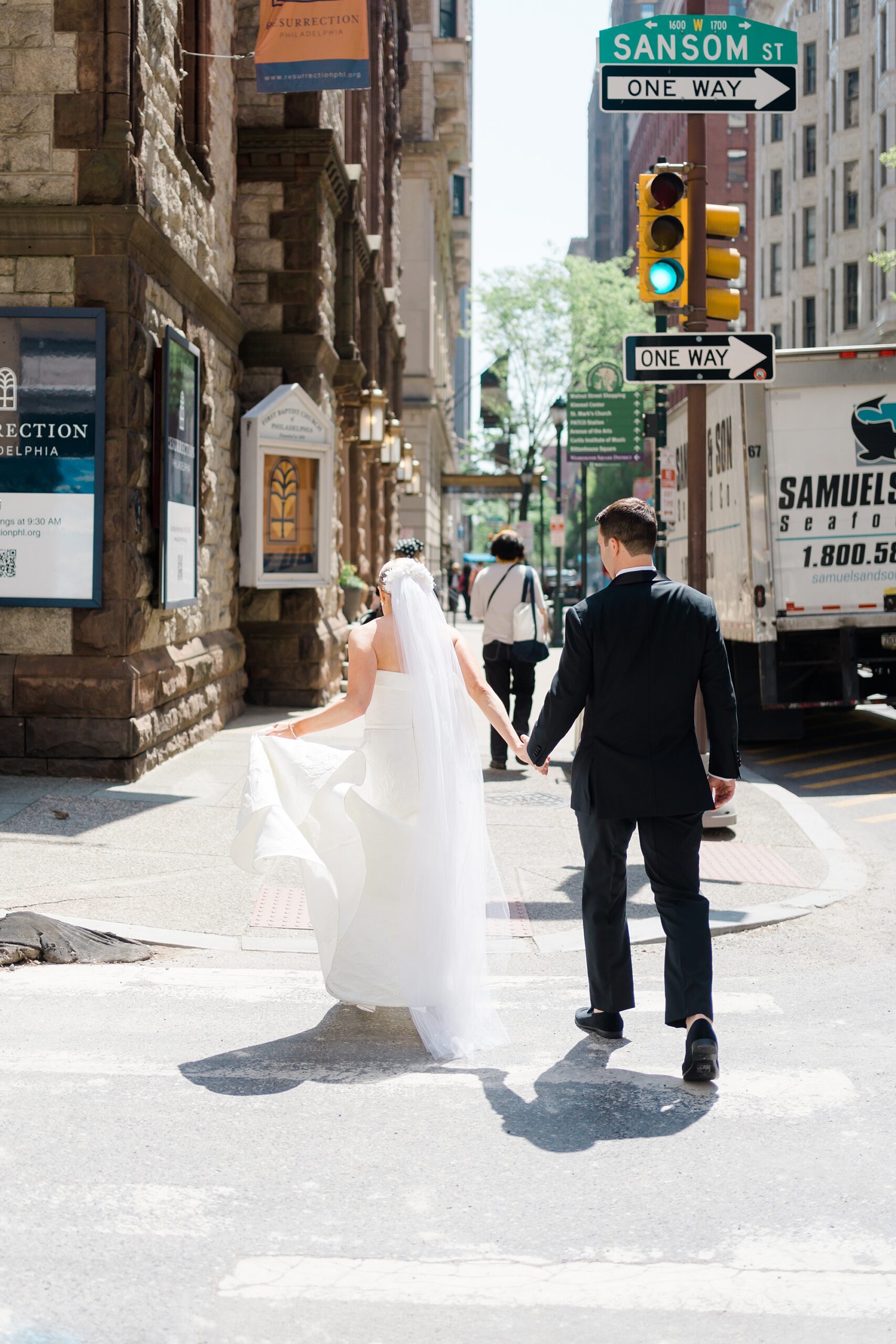 bride and groom walk down street holding hands