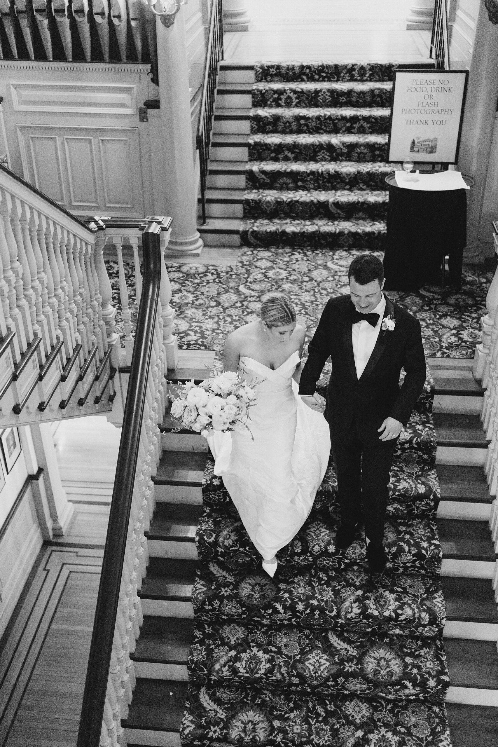 bride and groom holding hands walking down stairs 