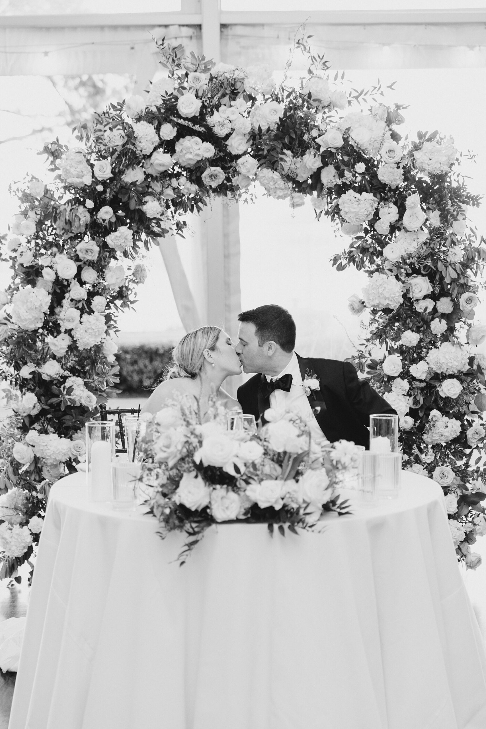 newlyweds kiss at sweetheart table at reception at Glen Foerd on the Delaware