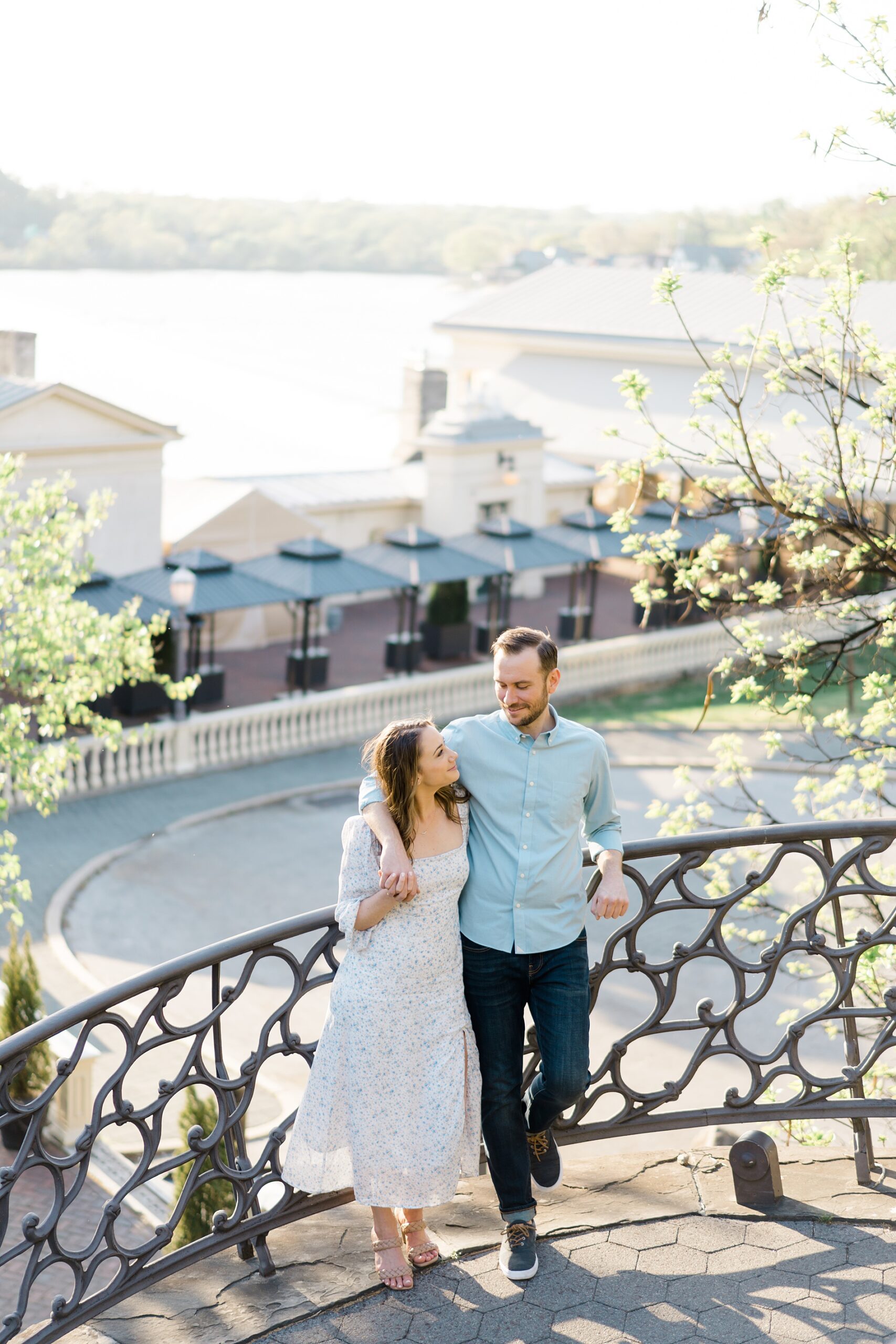 engaged couple lean against wrought iron fence during engagement session
