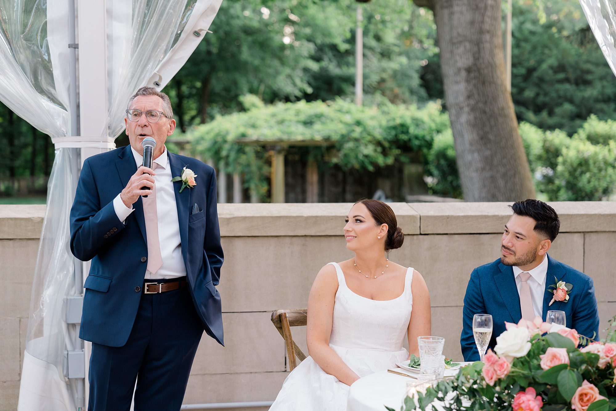 bride and groom listen to wedding speeches 