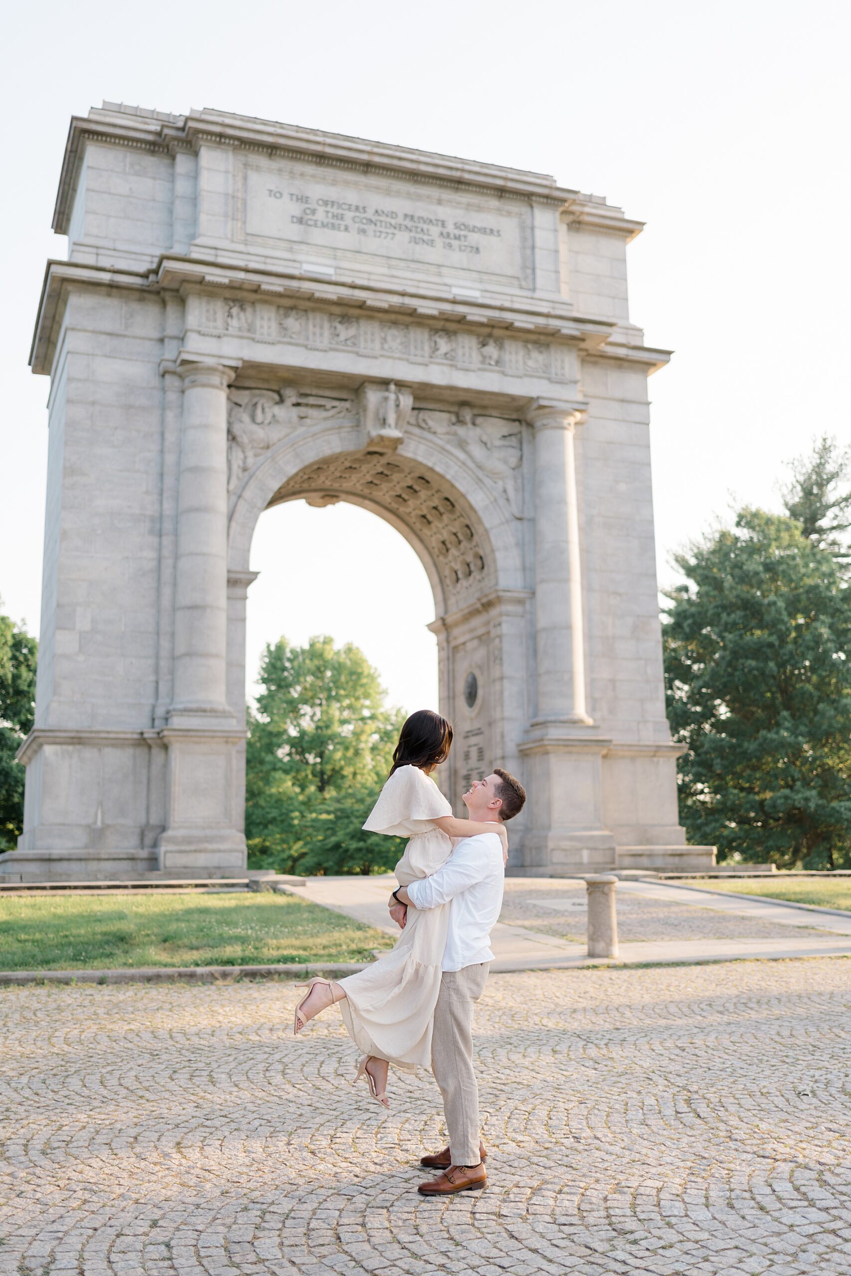 guy lifts his fiance up in front of National Memorial Arch