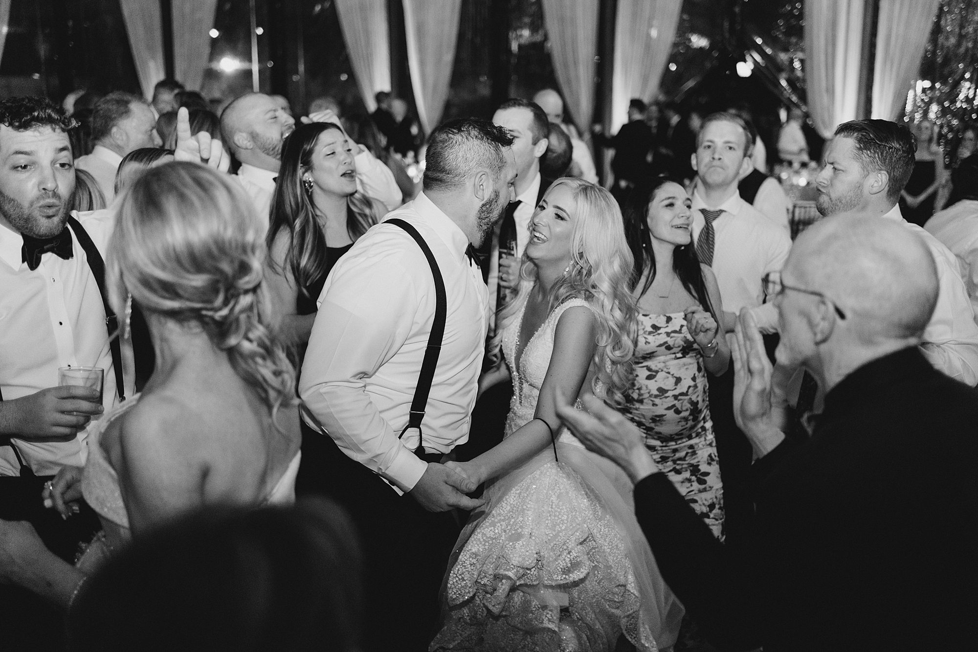 newlyweds dance at reception surrounded by wedding guests