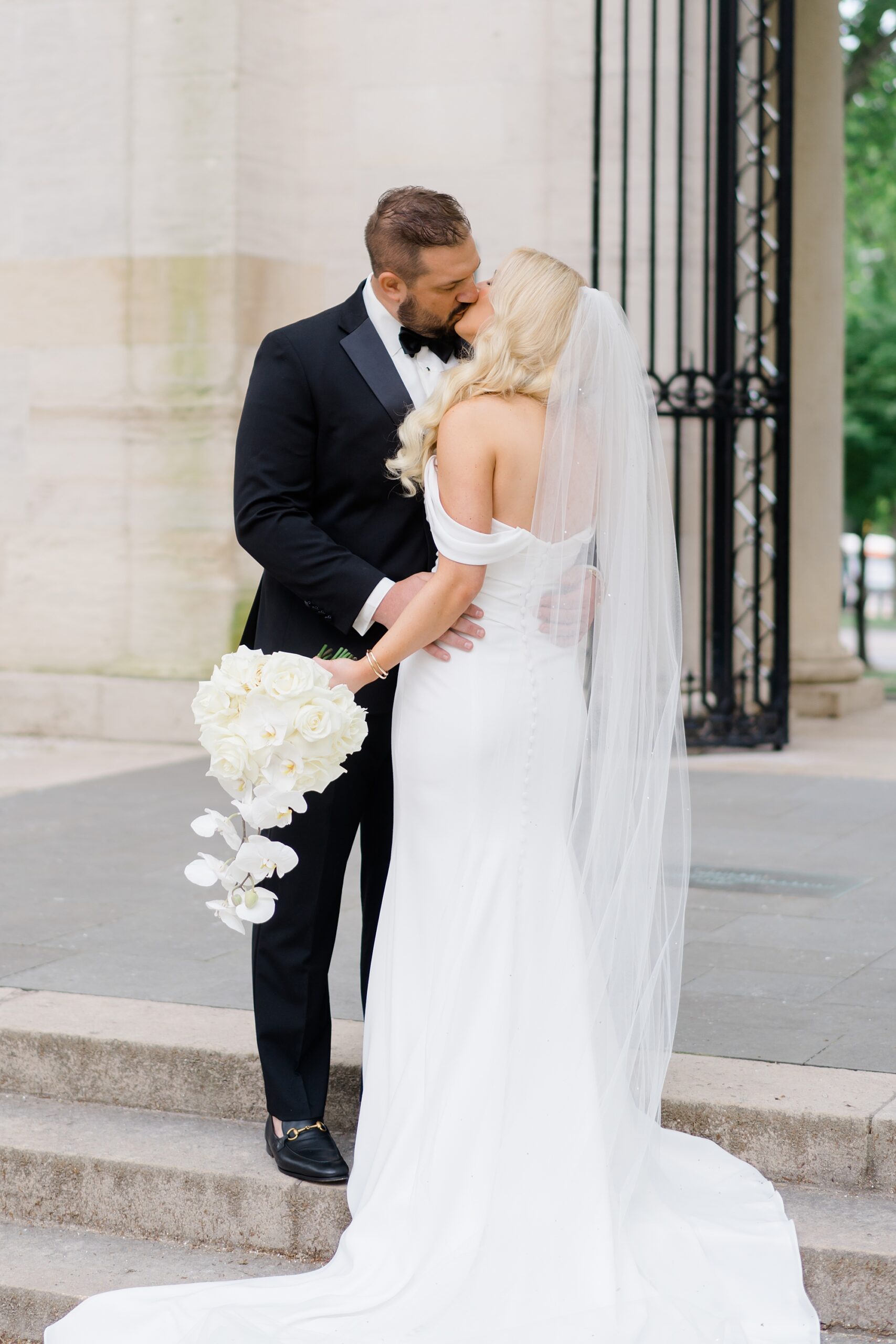 bride and groom kiss in front of Rodin Museum 