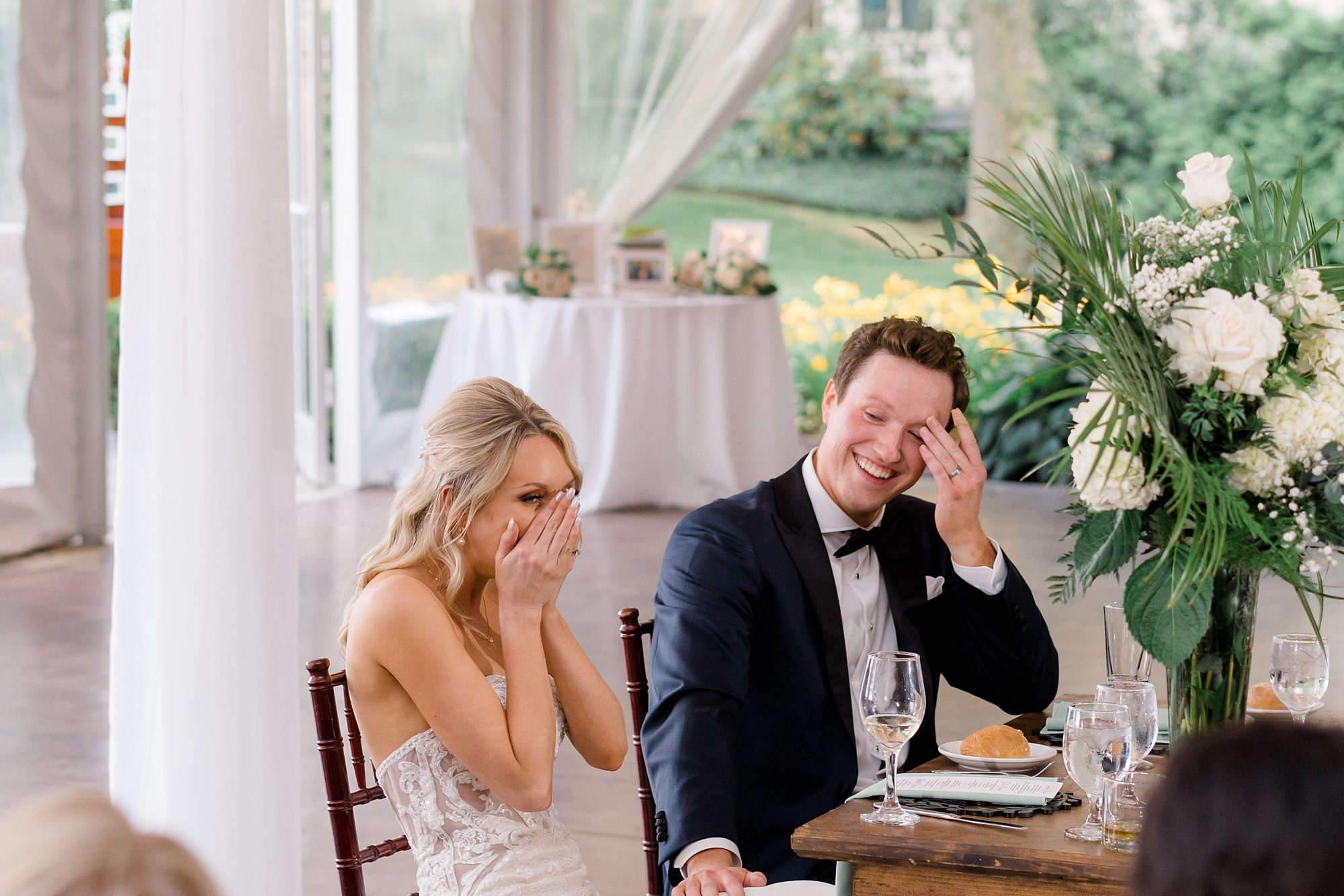 newlyweds laughing during wedding speeches