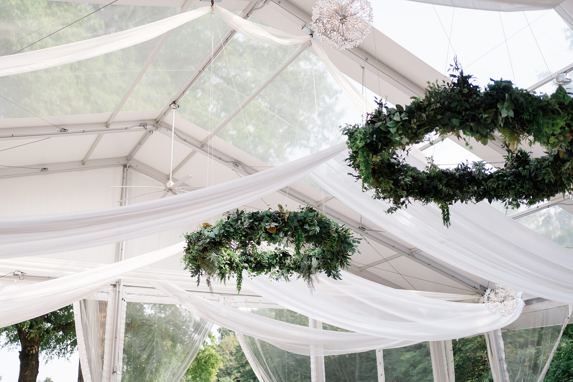 circular chandeliers in green vines hanging from reception tent