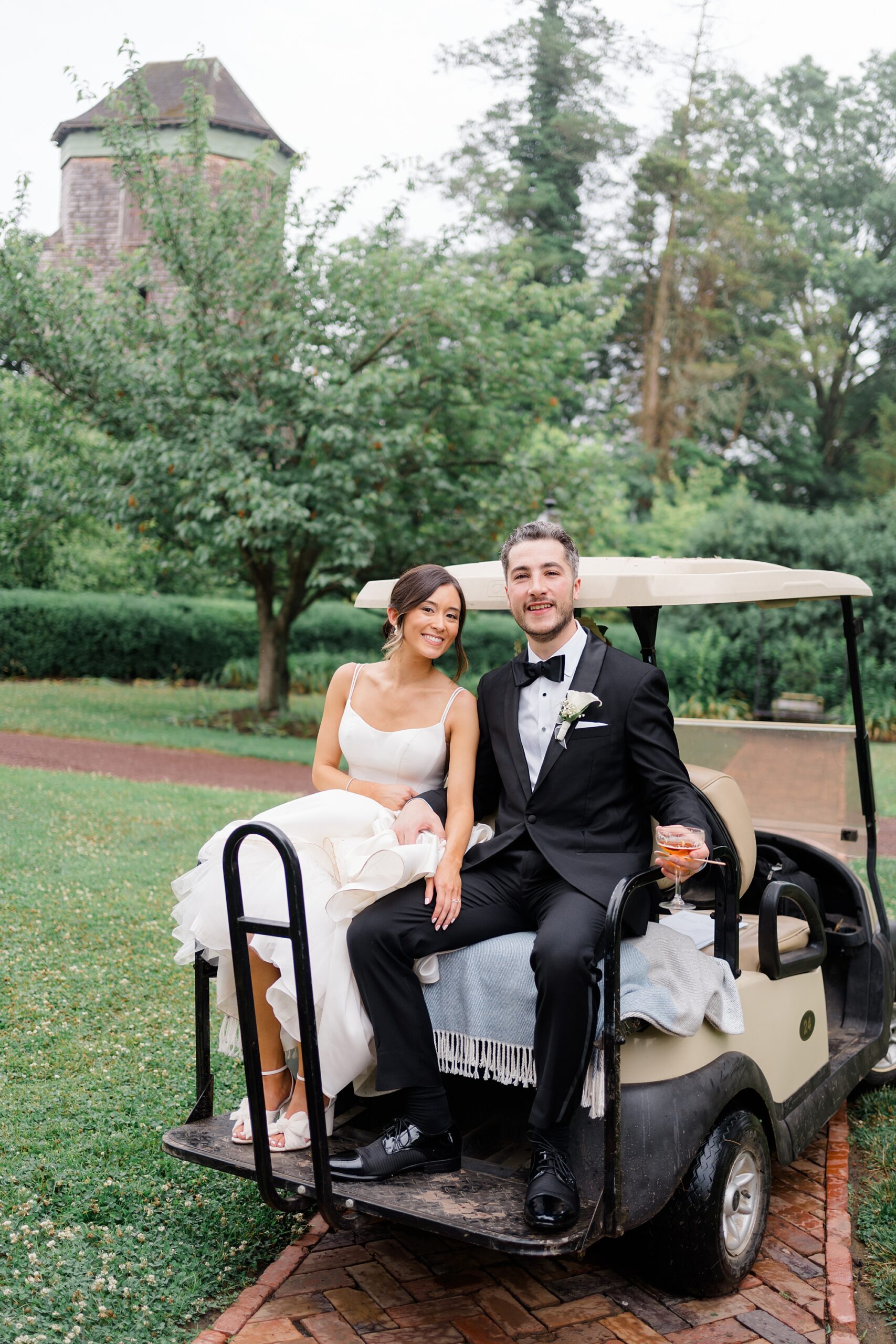 bride and groom sit on golf cart to go to reception