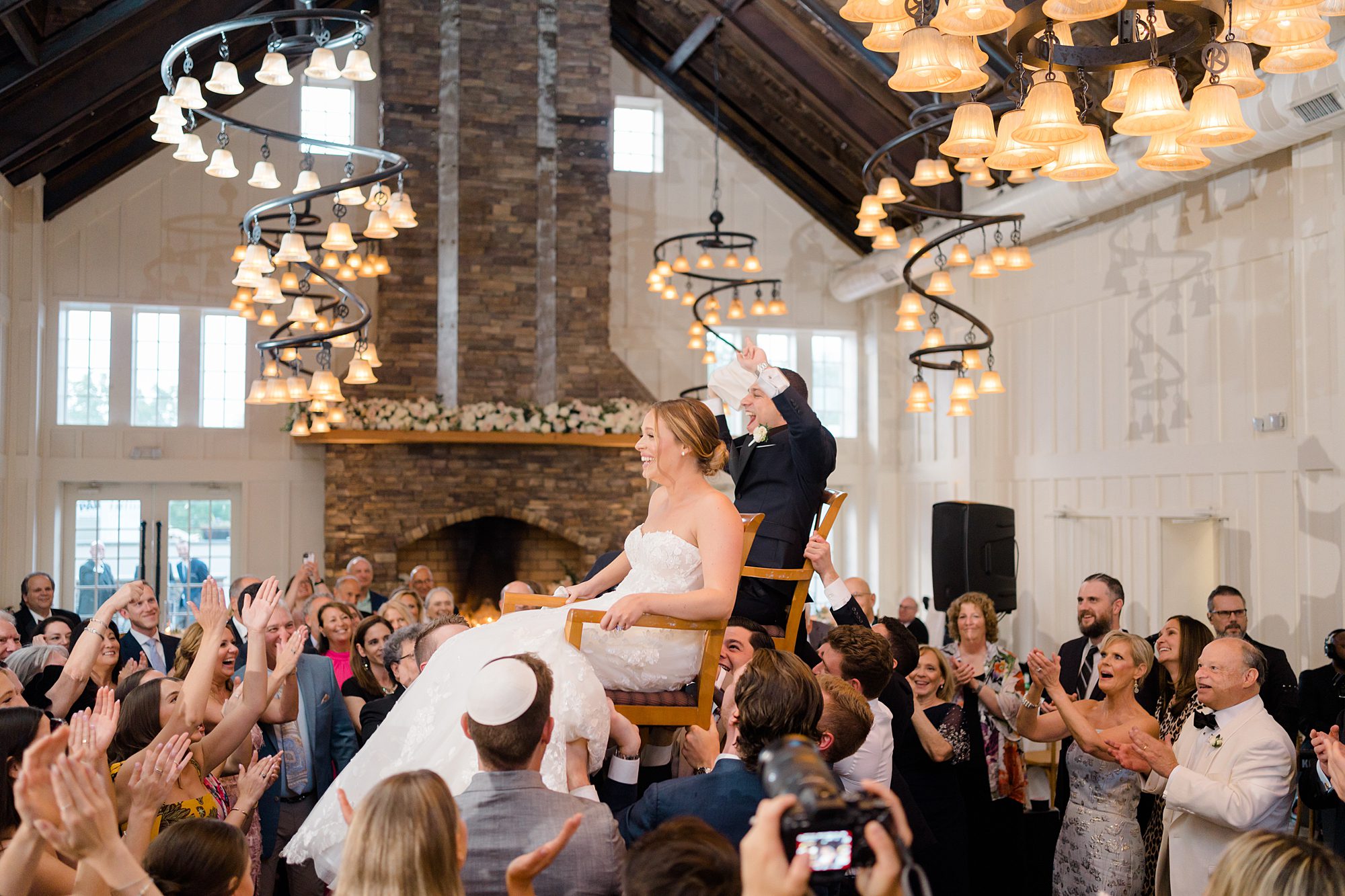 bride and groom are lifted up in the air on chairs during wedding reception