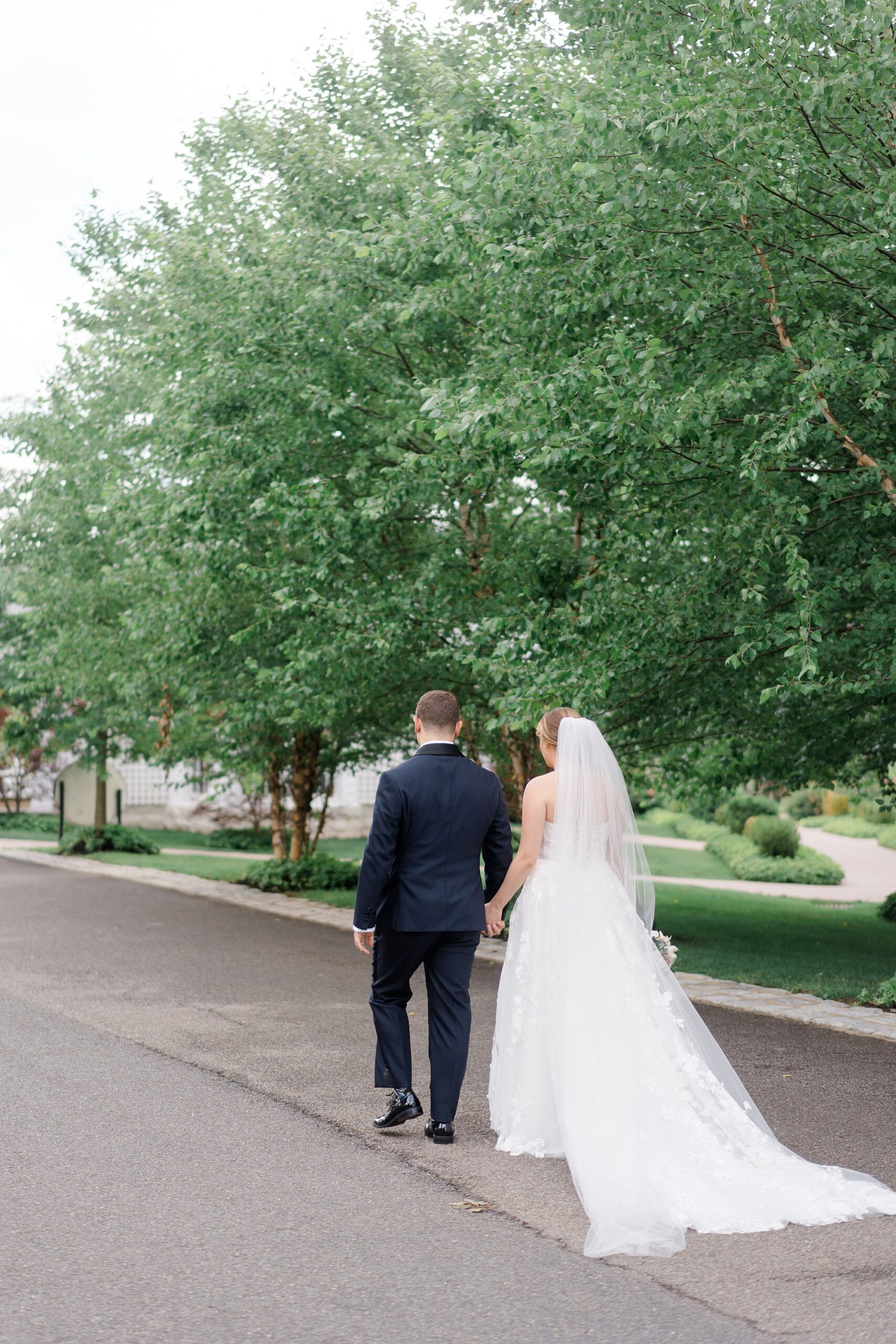 bride and groom walk down road at The Ryland Inn