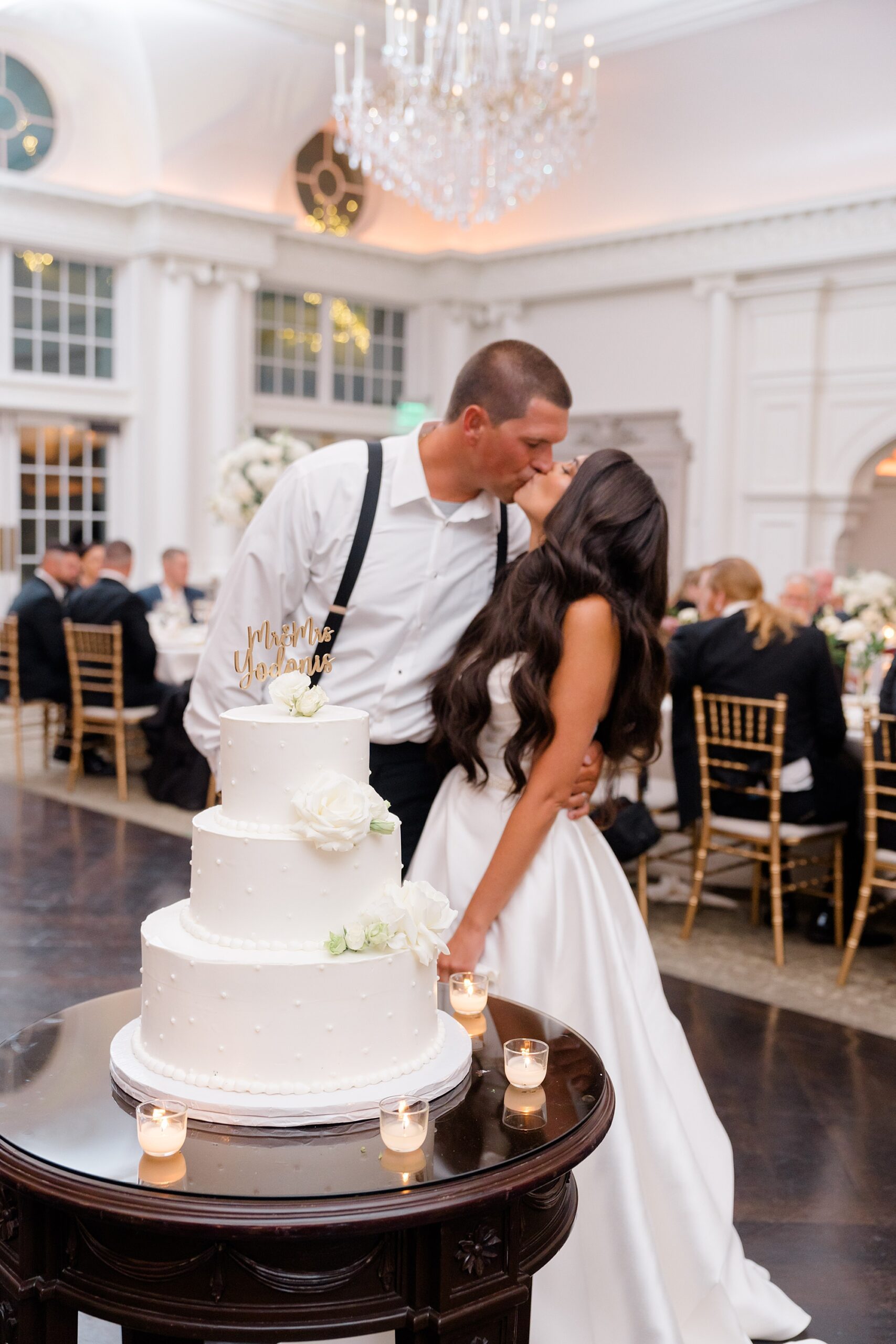 bride and groom kiss by wedding cake