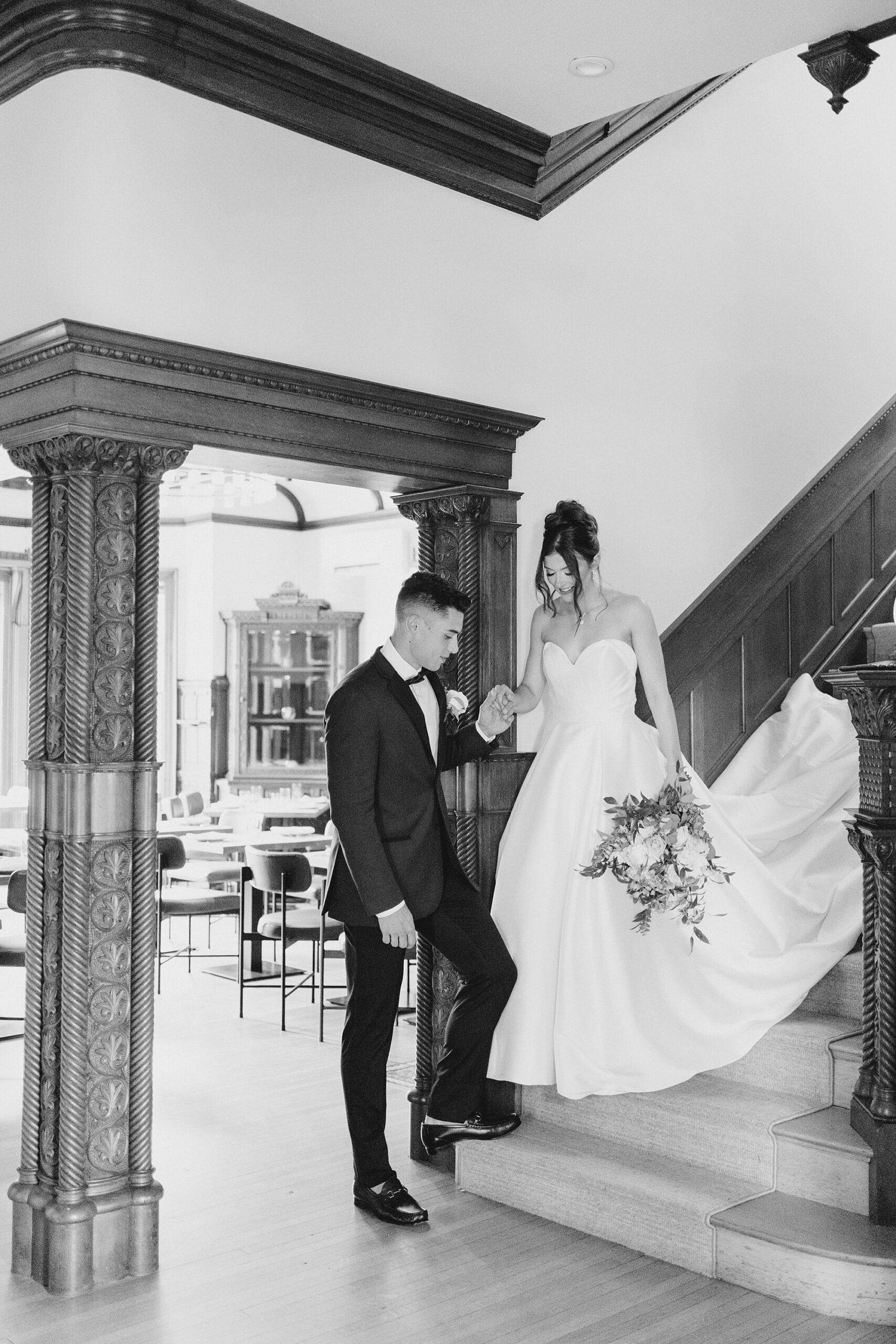 bride and groom walk down staircase inside mansion
