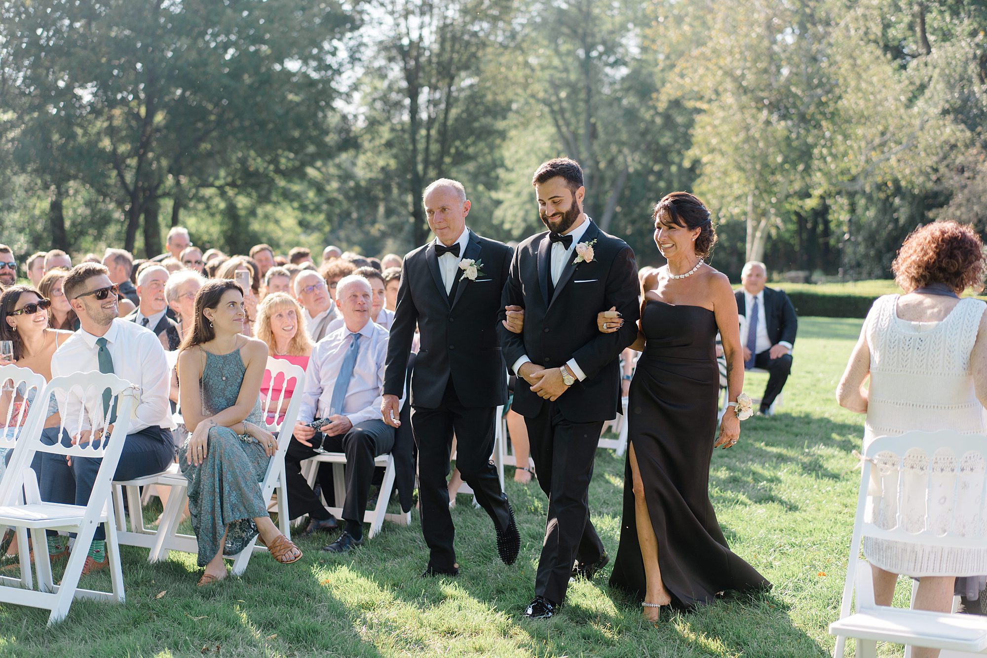 groom walks down the aisle with his parents