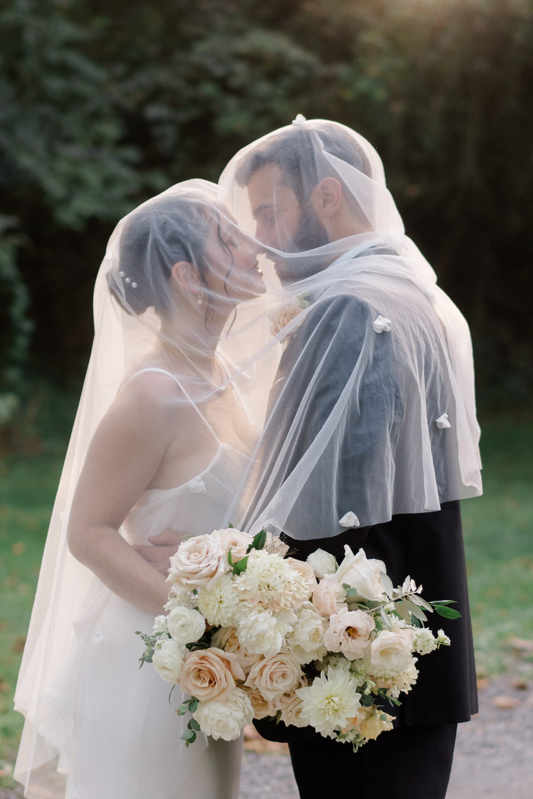 newlyweds kiss under bride's veil during wedding portraits