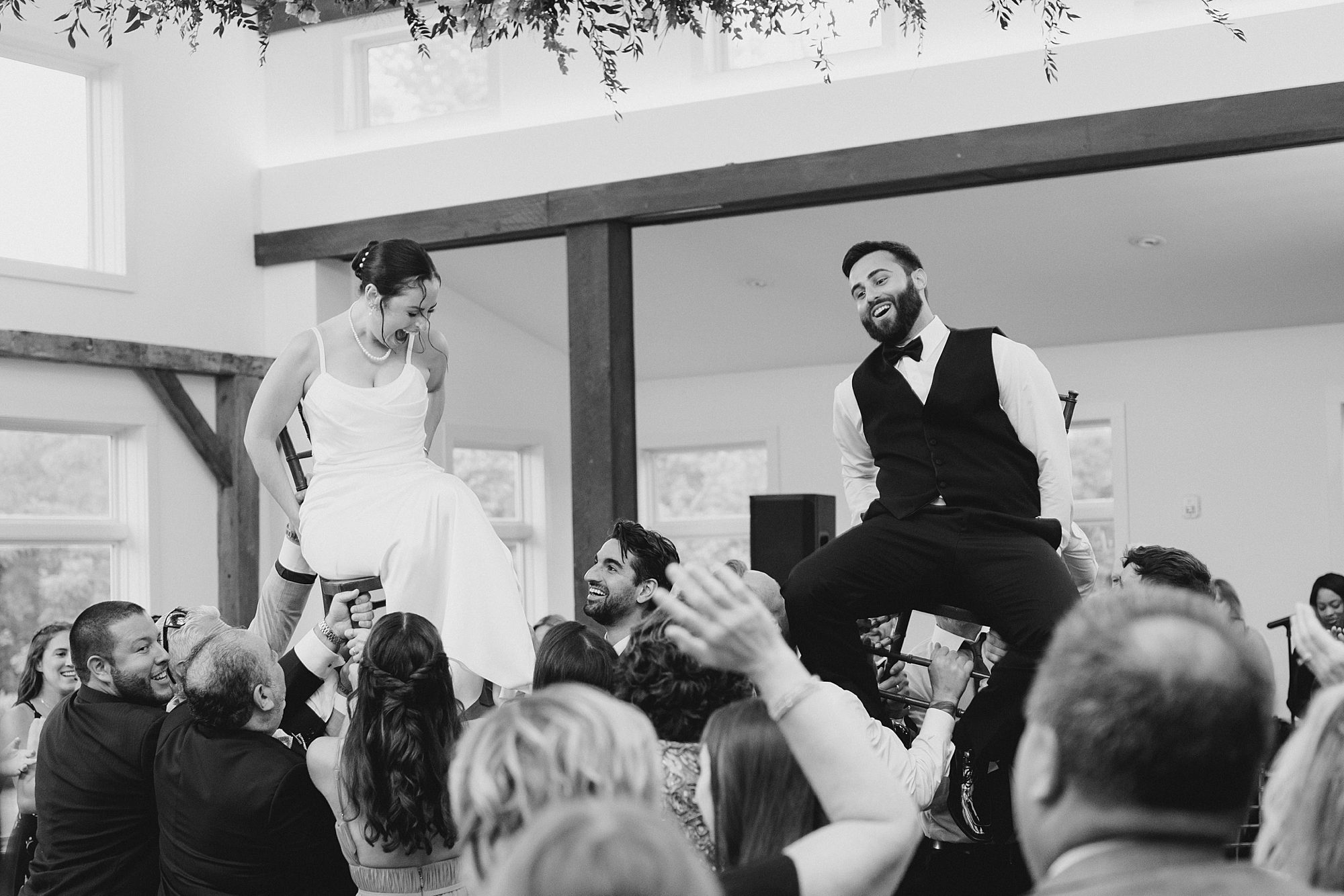 bride and groom are lifted up in chairs