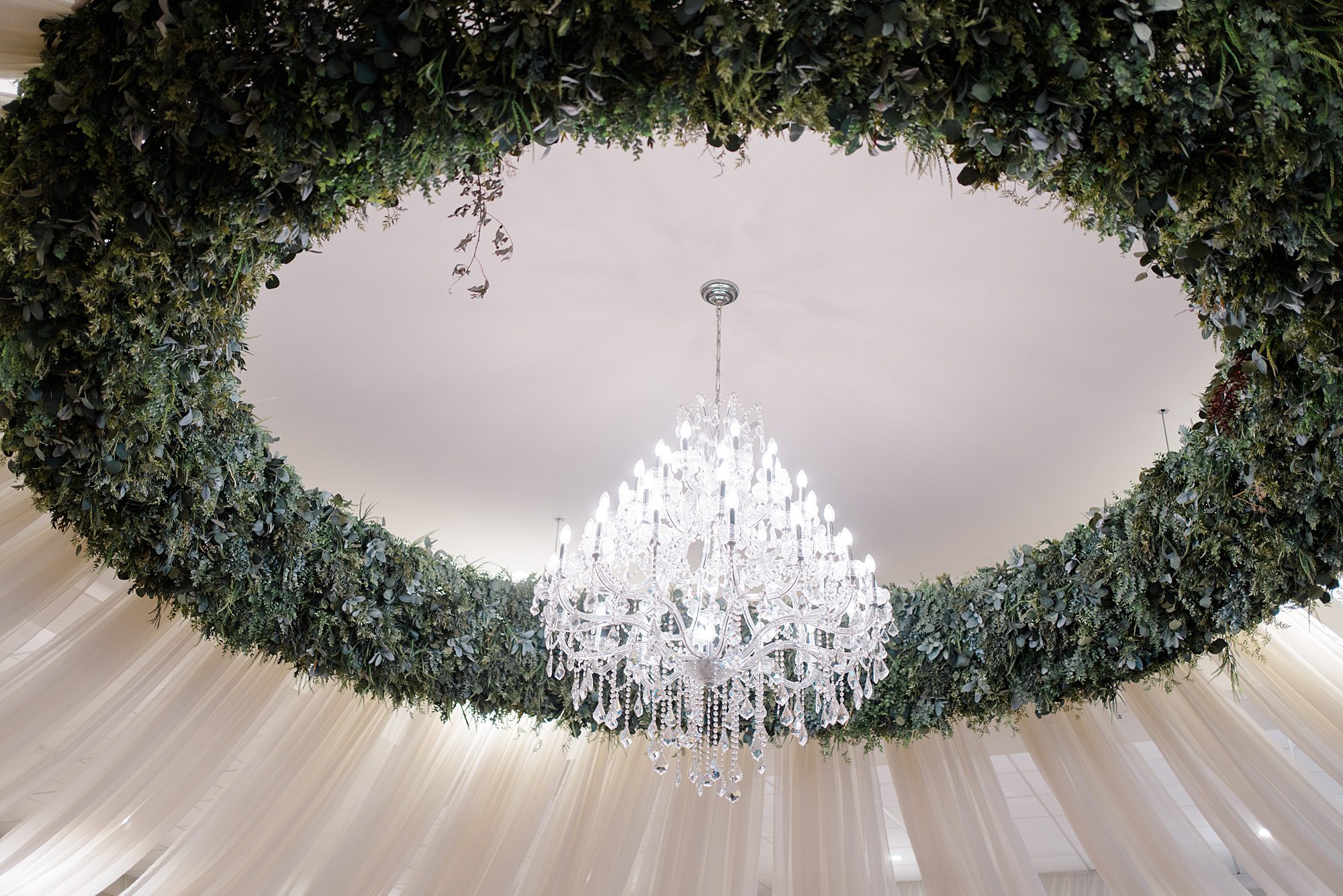 crystal chandelier surrounded by circular greenery detail