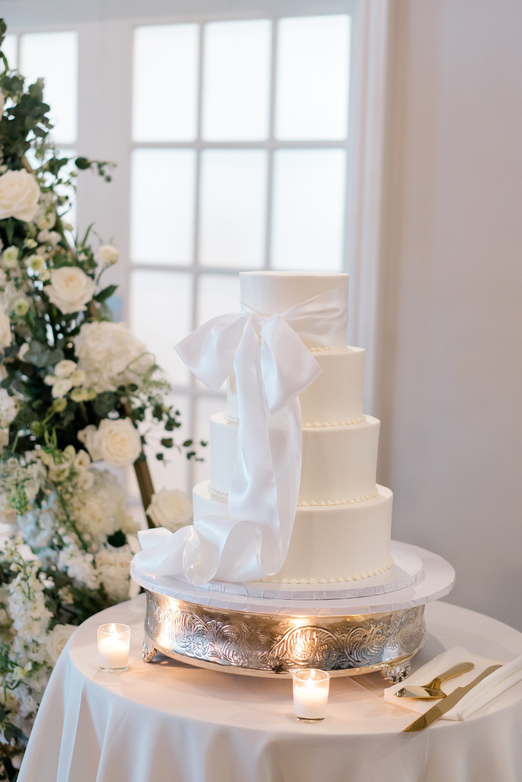 white modern white cake with bow around it 