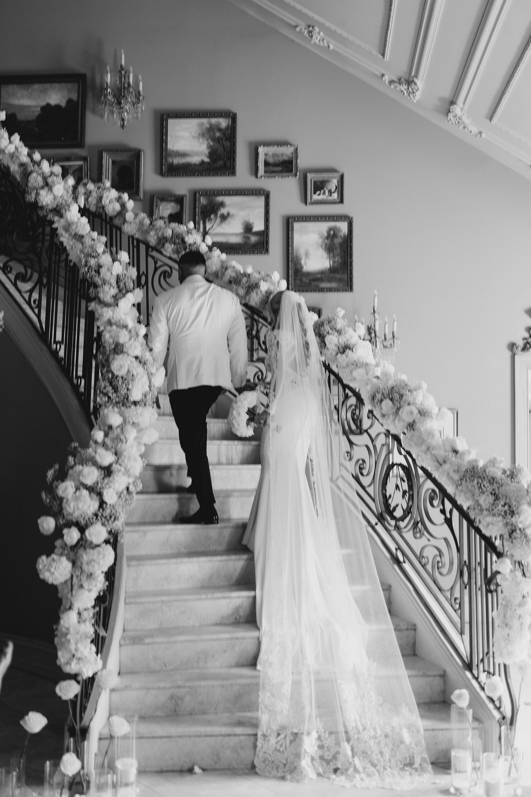 bride and groom walk up grand spiral staircase