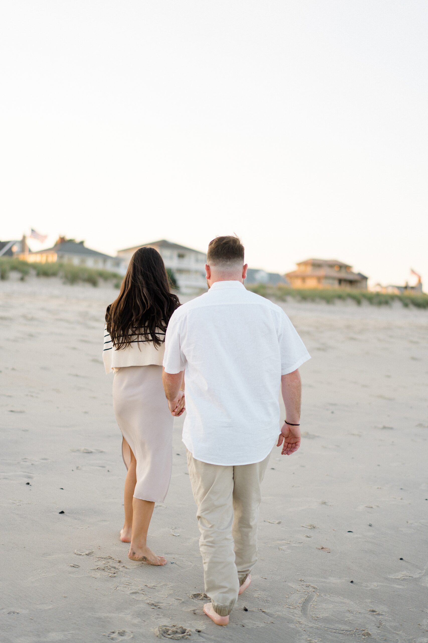 engaged couple walk beach together during engagement portraits