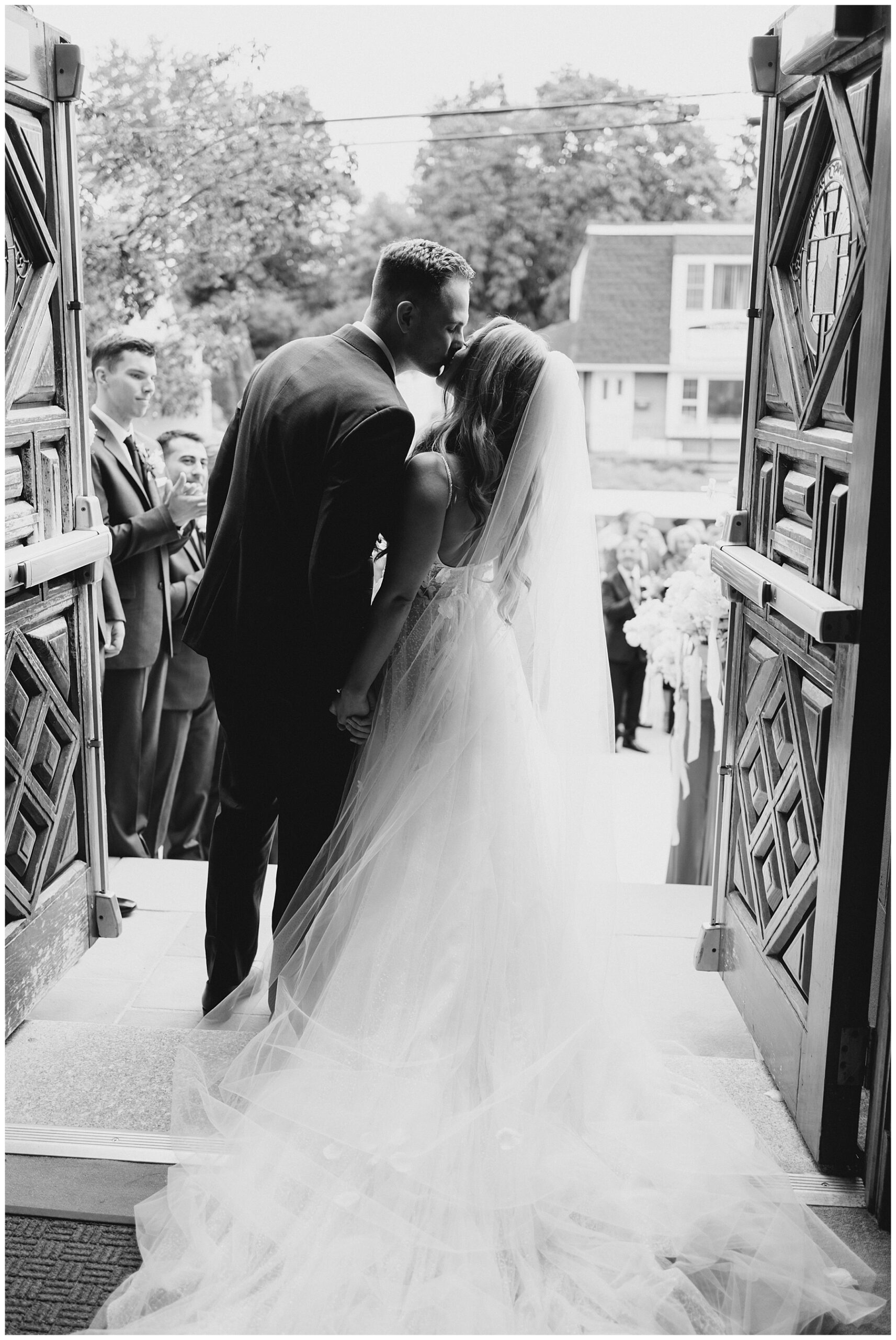 bride and groom kiss at the doors of church 