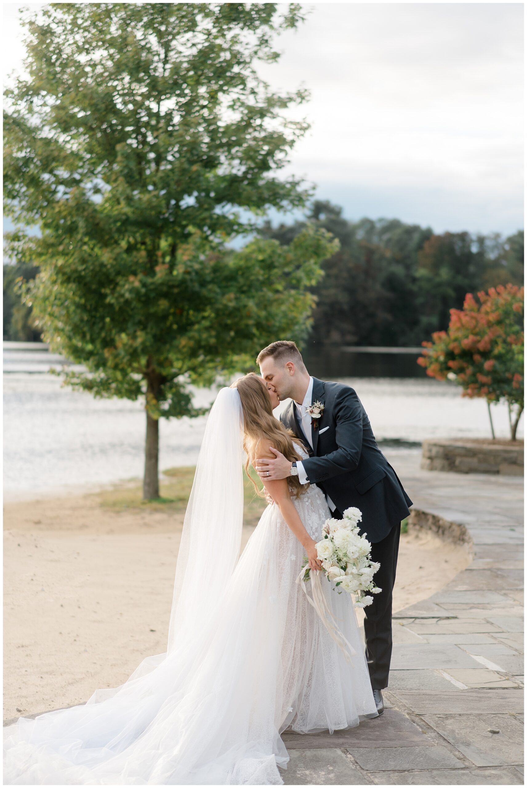 newlyweds kiss by lakeside wedding venue