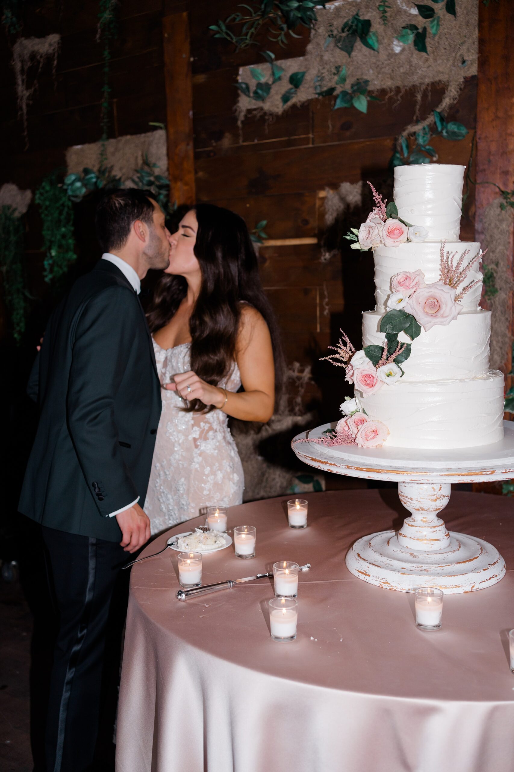 newlyweds kiss by wedding cake