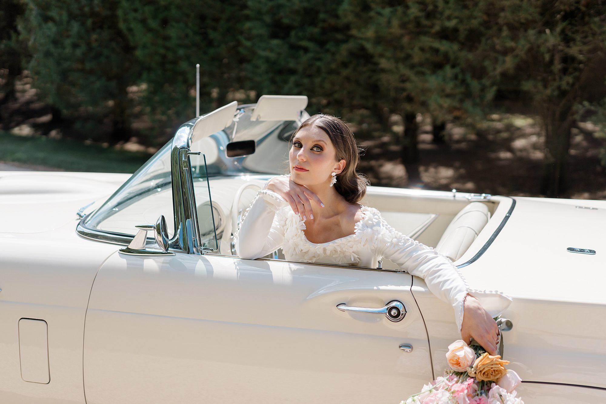 Bride sits in ivory classic car
