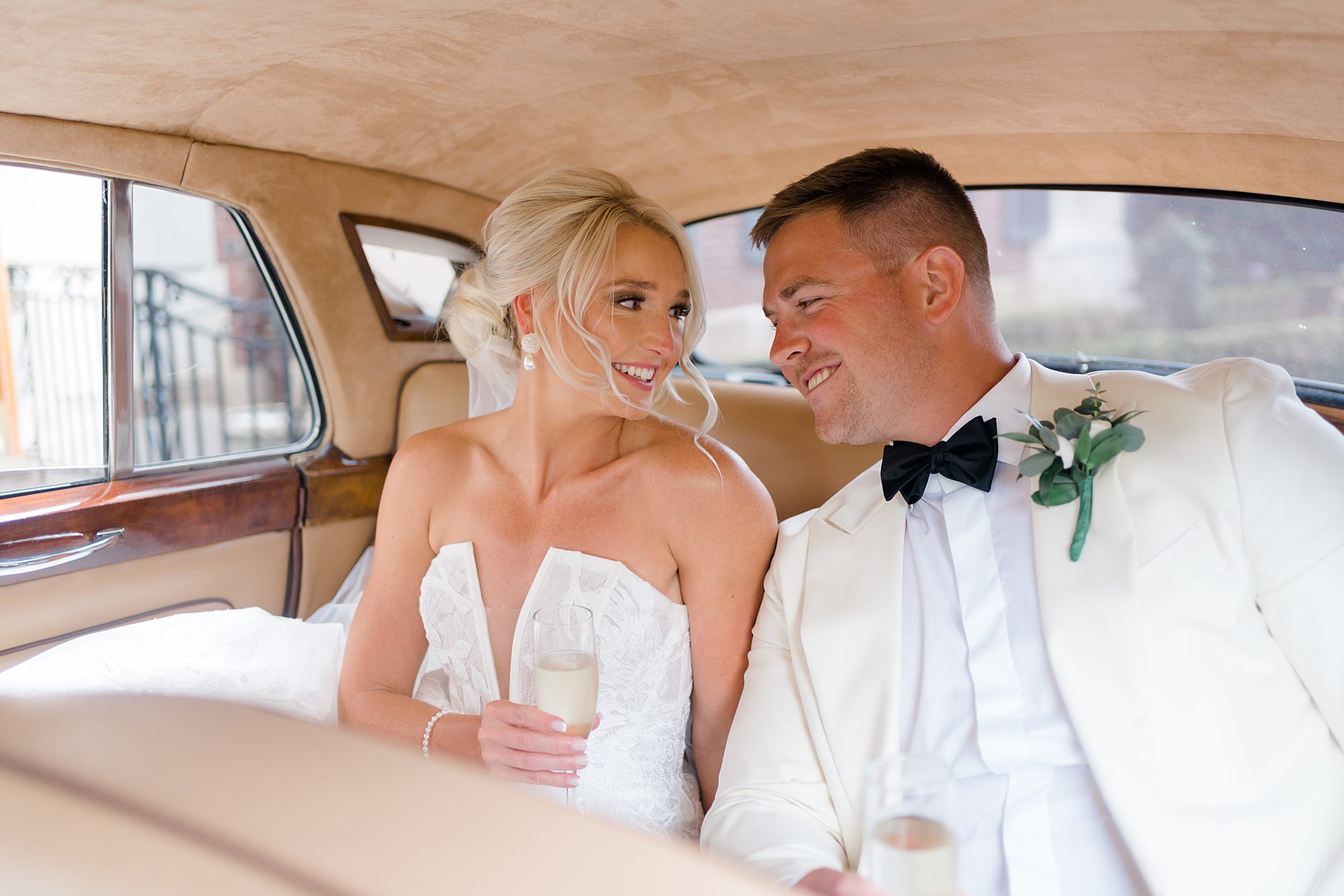 newlyweds sip champagne in the back of Rolls Royce