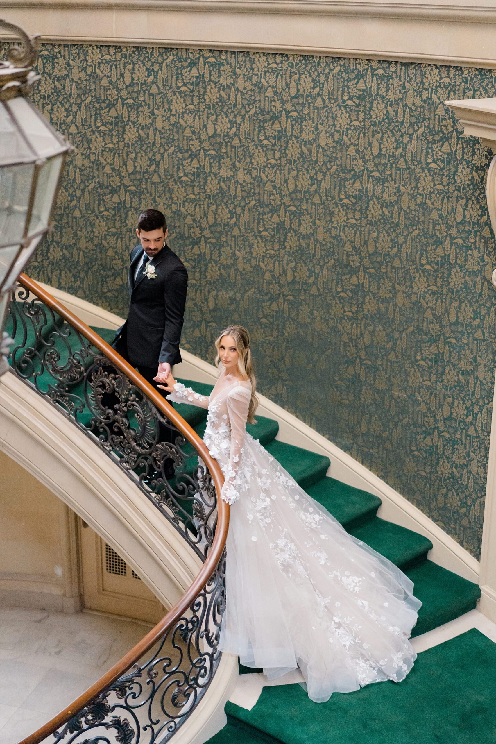 bride and groom walk up spiral staircase 