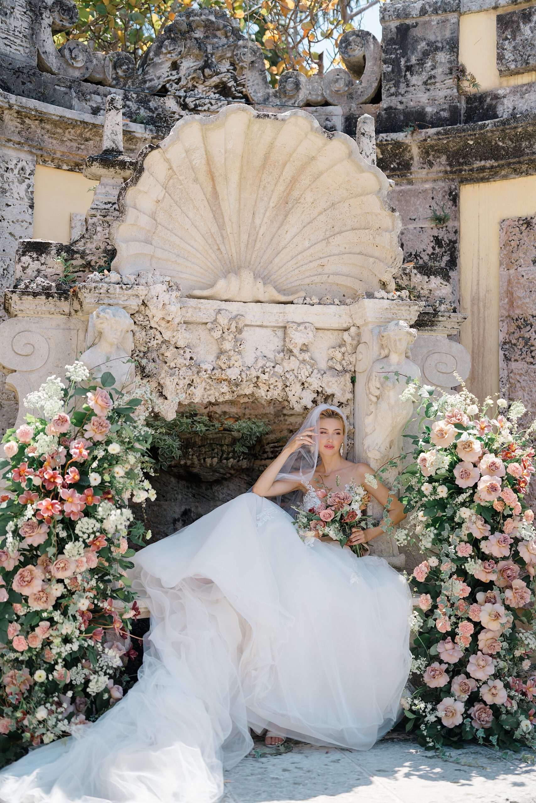 bride sits in courtyard surrounded by flowers