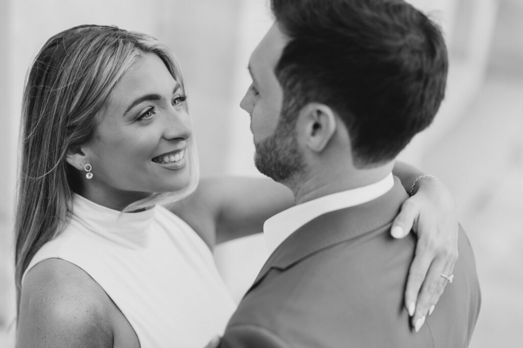 Black and White Image of Bride smiling at groom during engagement session at Merchants' Exchange in Philadelphia