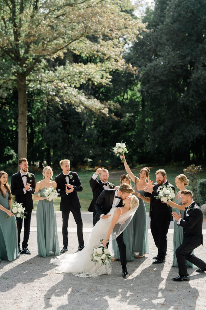 Bridal party cheers for bride and groom while they kiss at Curtis Arboretum wedding