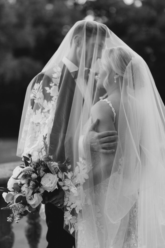 Black and white image of bride and groom under brides veil at Curtis Arboretum wedding
