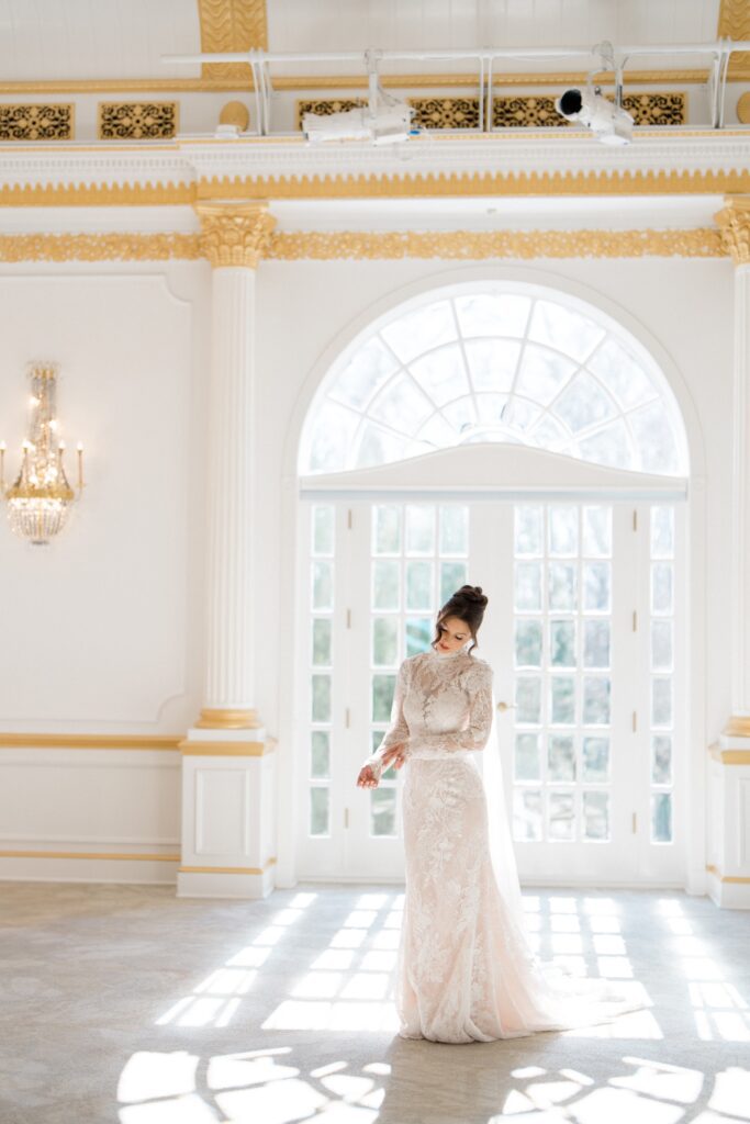 Bride posing in front of a giant window with the sun shining through during styled shoot at Crystal Plaza