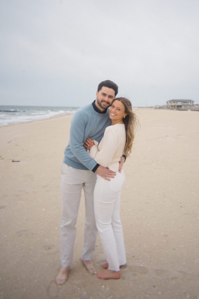 Couple standing arm in arm on the beach during Spring Lake Engagement
